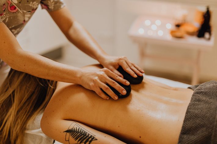 Learn More A woman is getting a massage with rocks on her back.