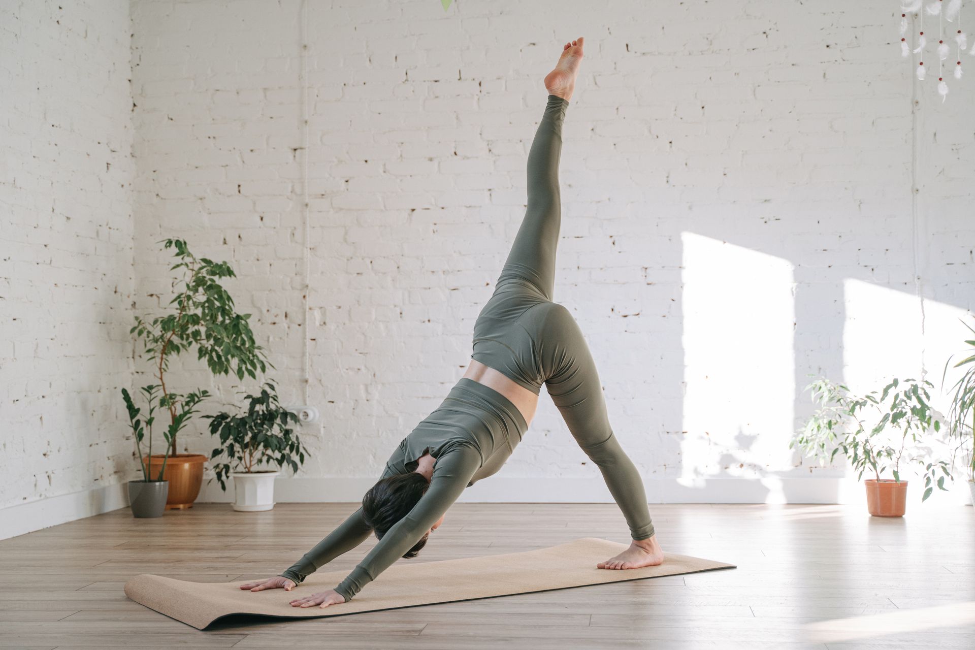 A woman is doing a yoga pose on a yoga mat in a room.