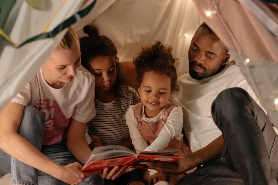 a family sits under a tent reading a book