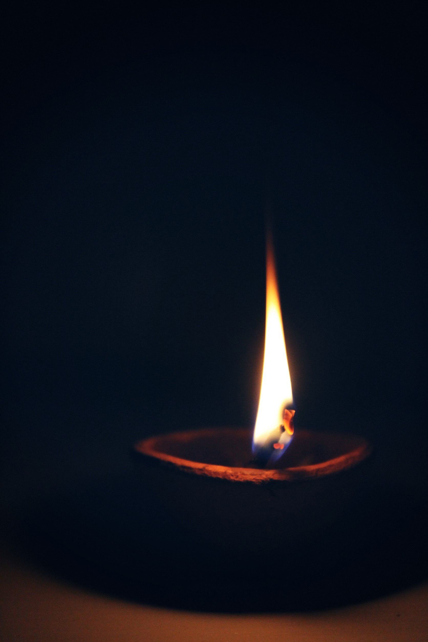 A small candle is lit up in the dark.