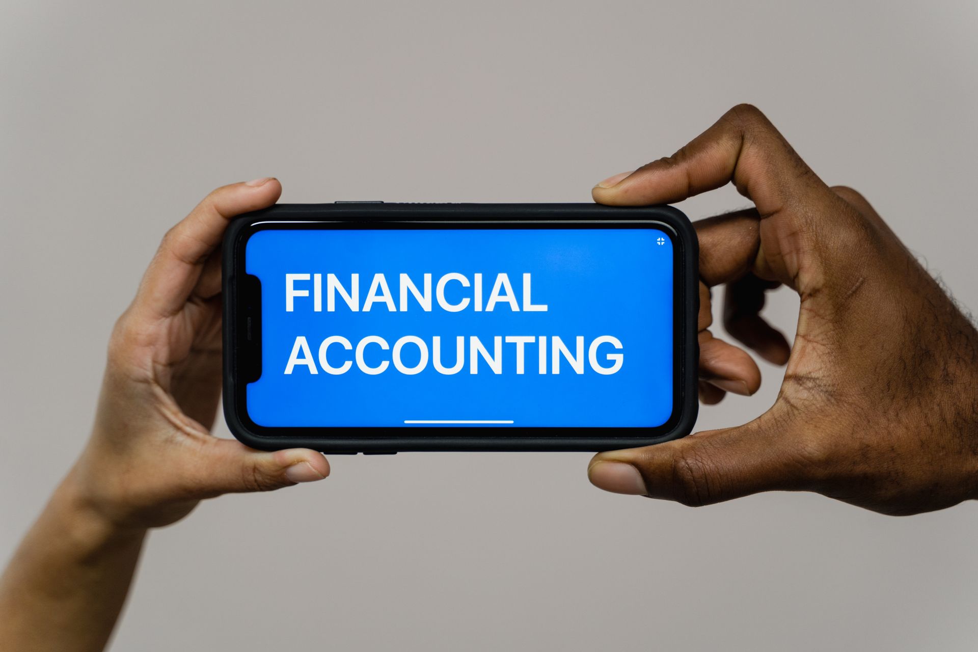 a person is holding a cell phone with the word financial accounting on the screen .