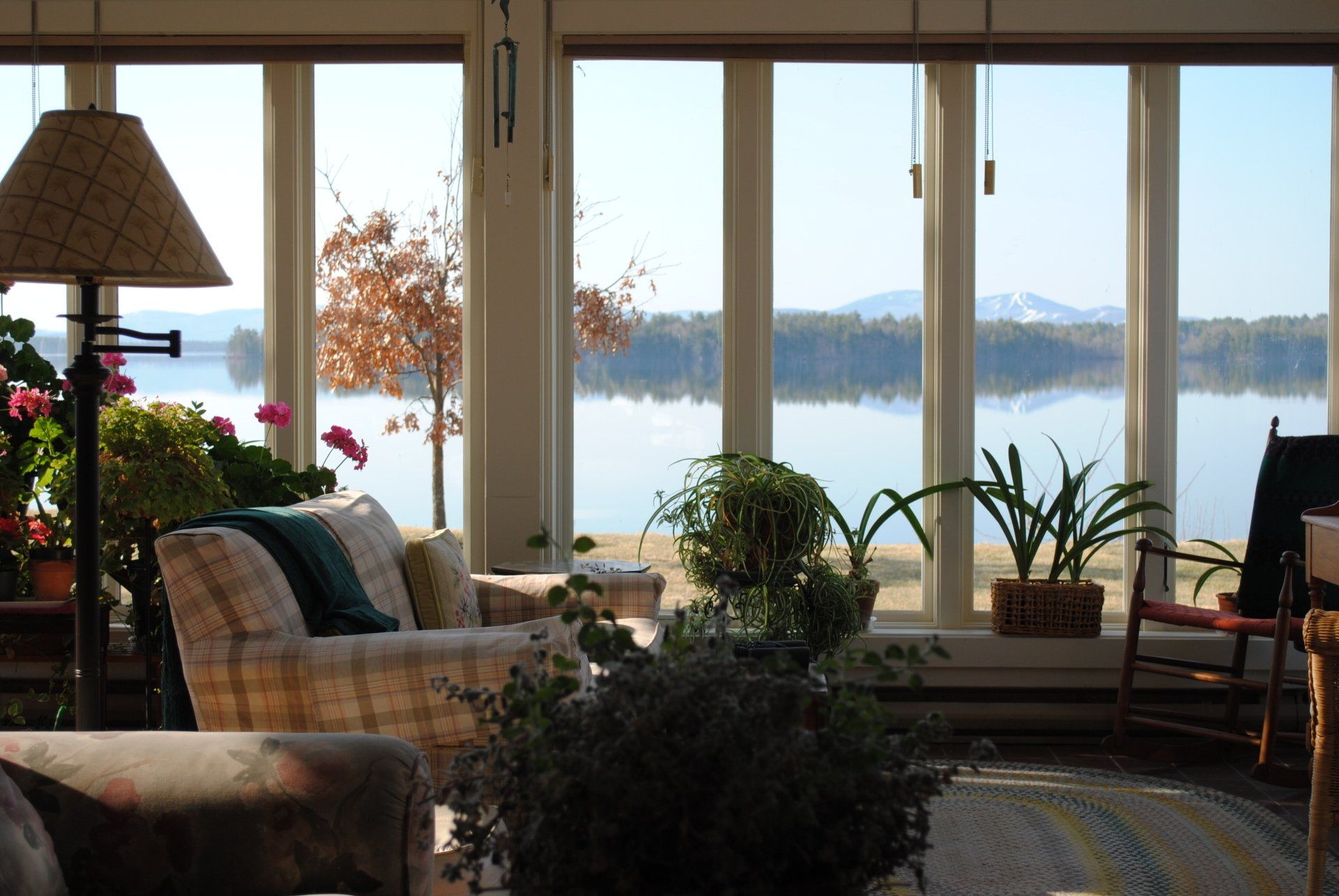 A living room with a view of a lake and hills.
