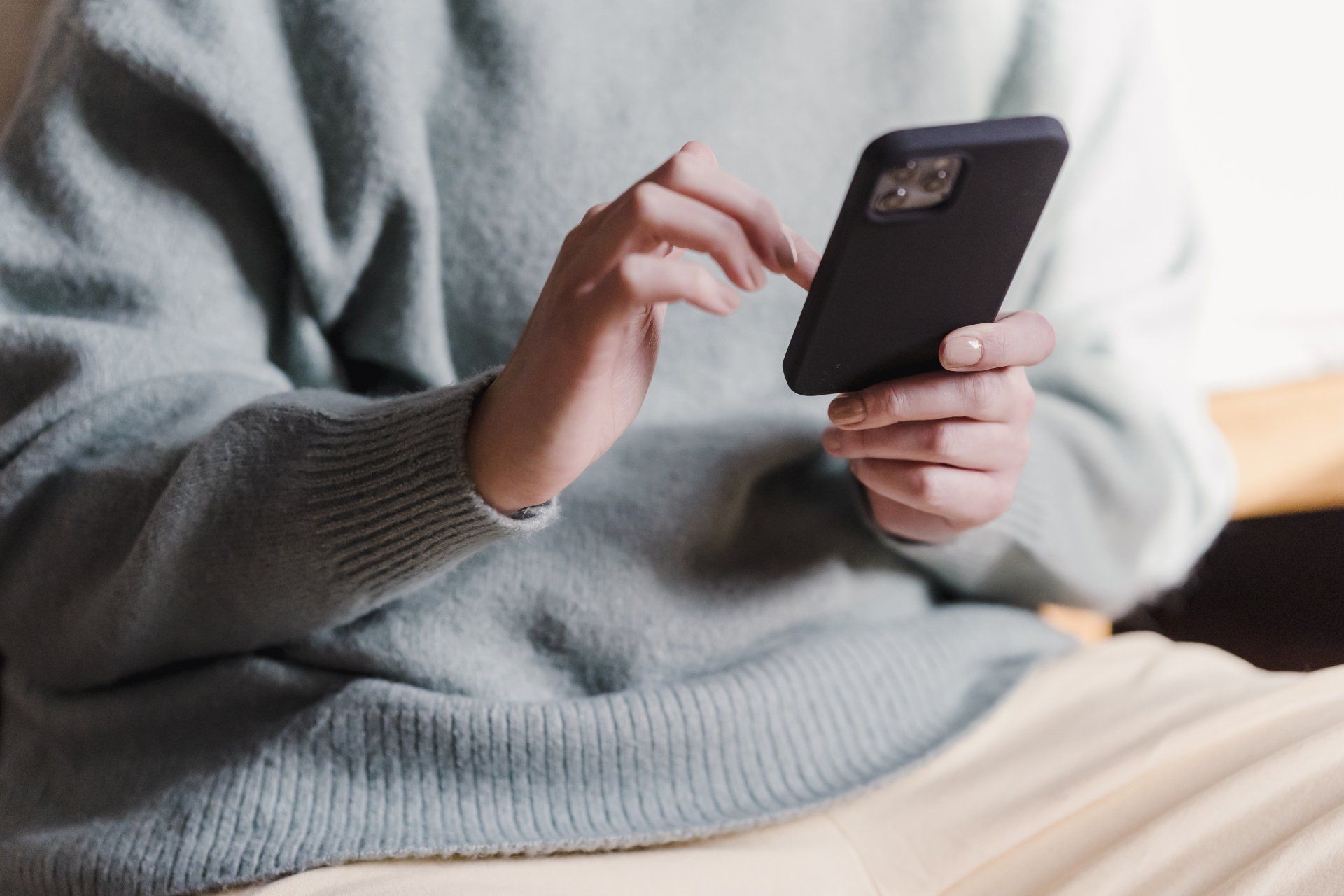 Una donna è seduta su un divano e chatta con lo smartphone