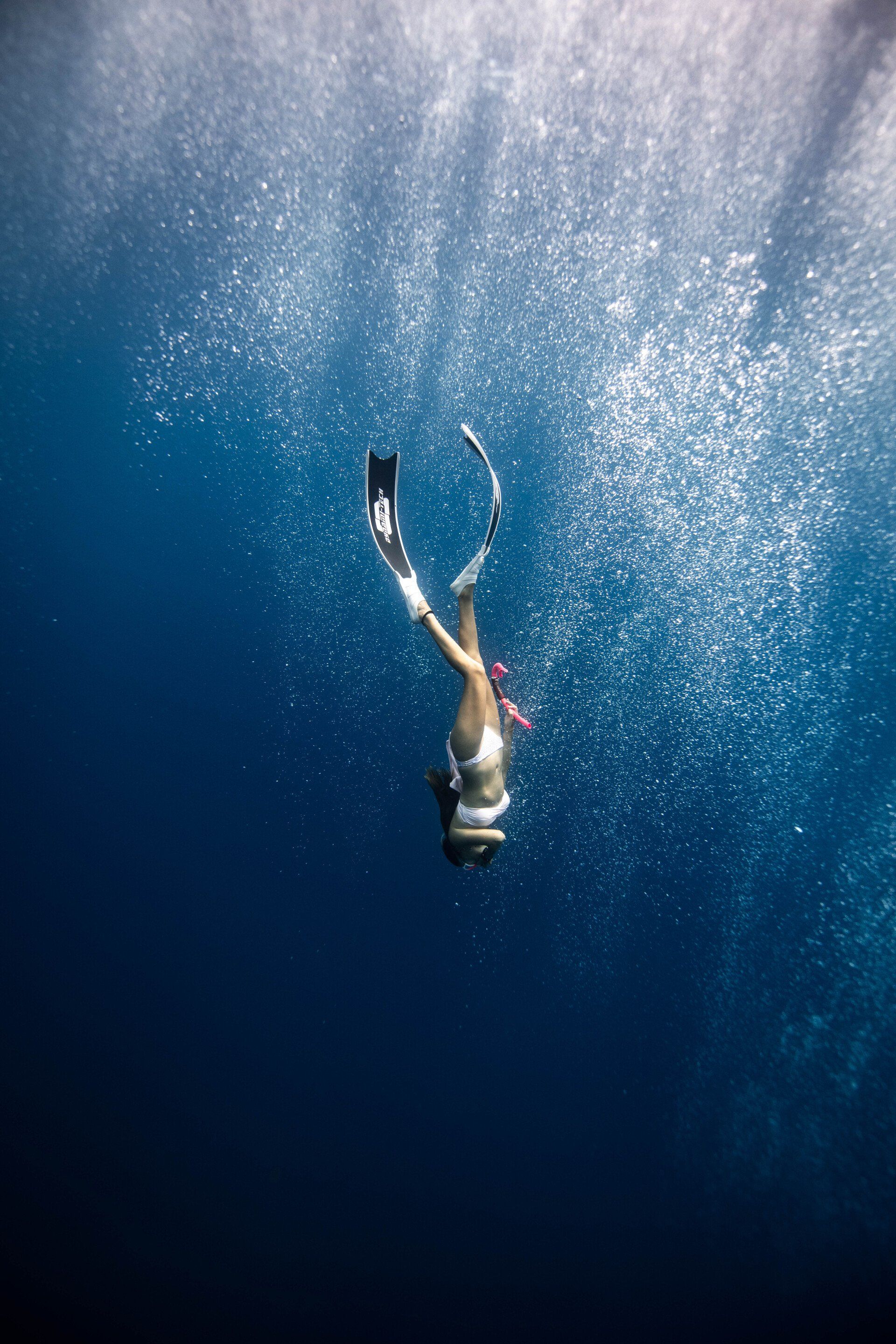 A woman is swimming underwater in the ocean.