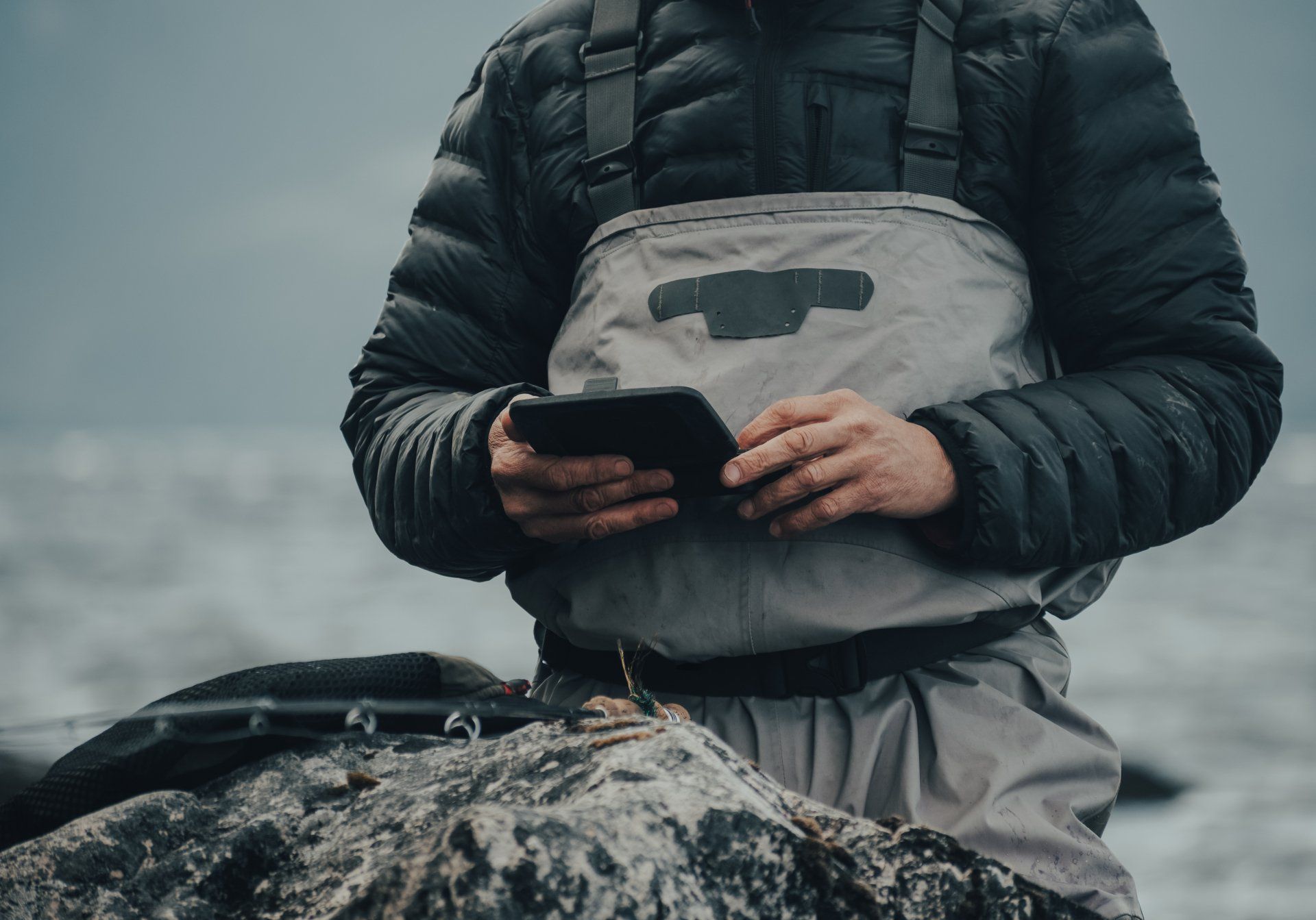A man is standing on a rock using a tablet computer.