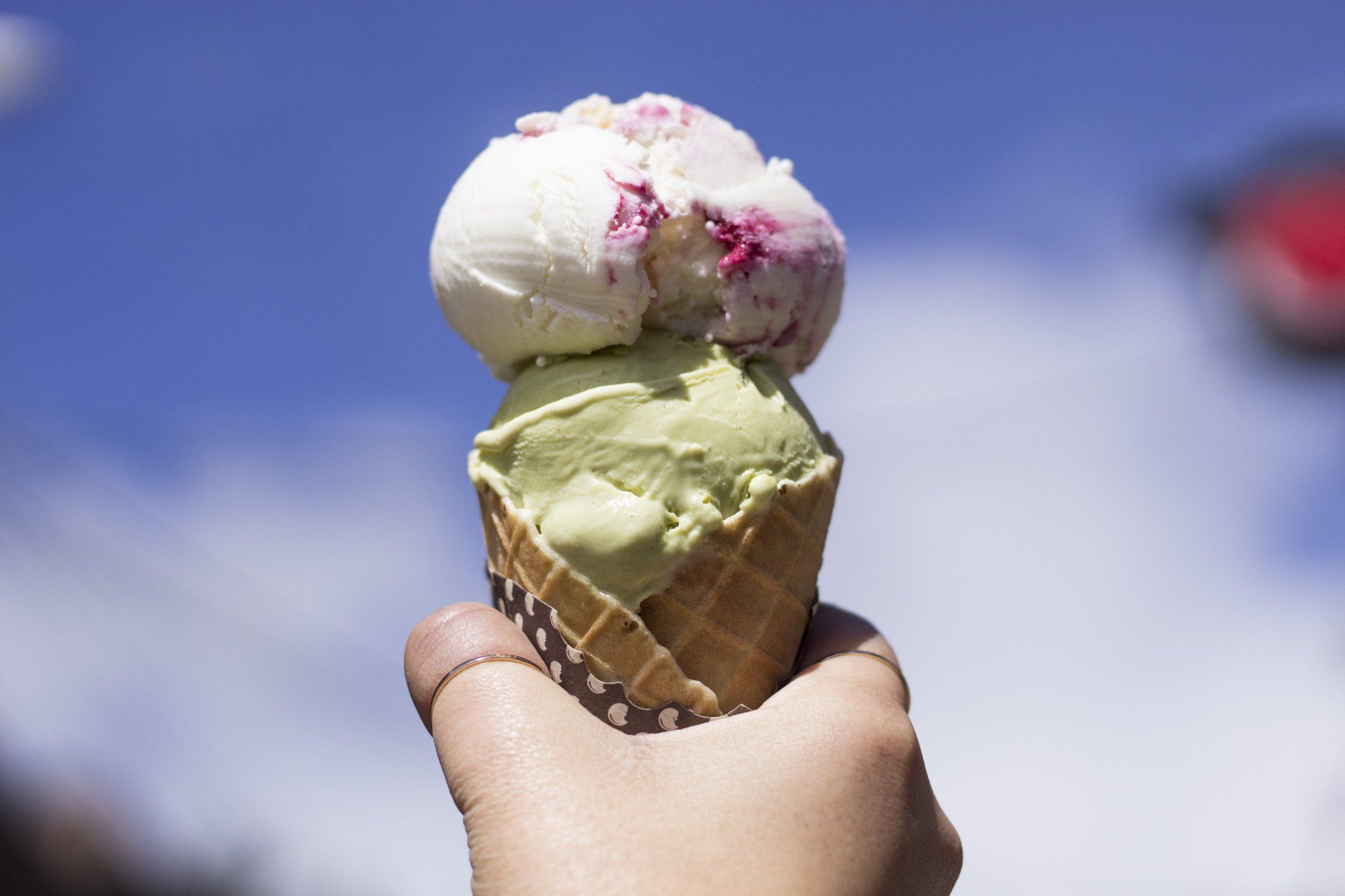 A person is holding two scoops of ice cream in a waffle cone.
