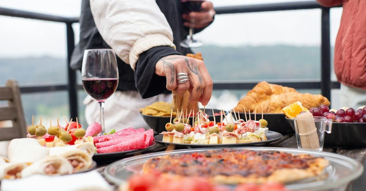 A person is cutting a piece of food on a table with a glass of wine.