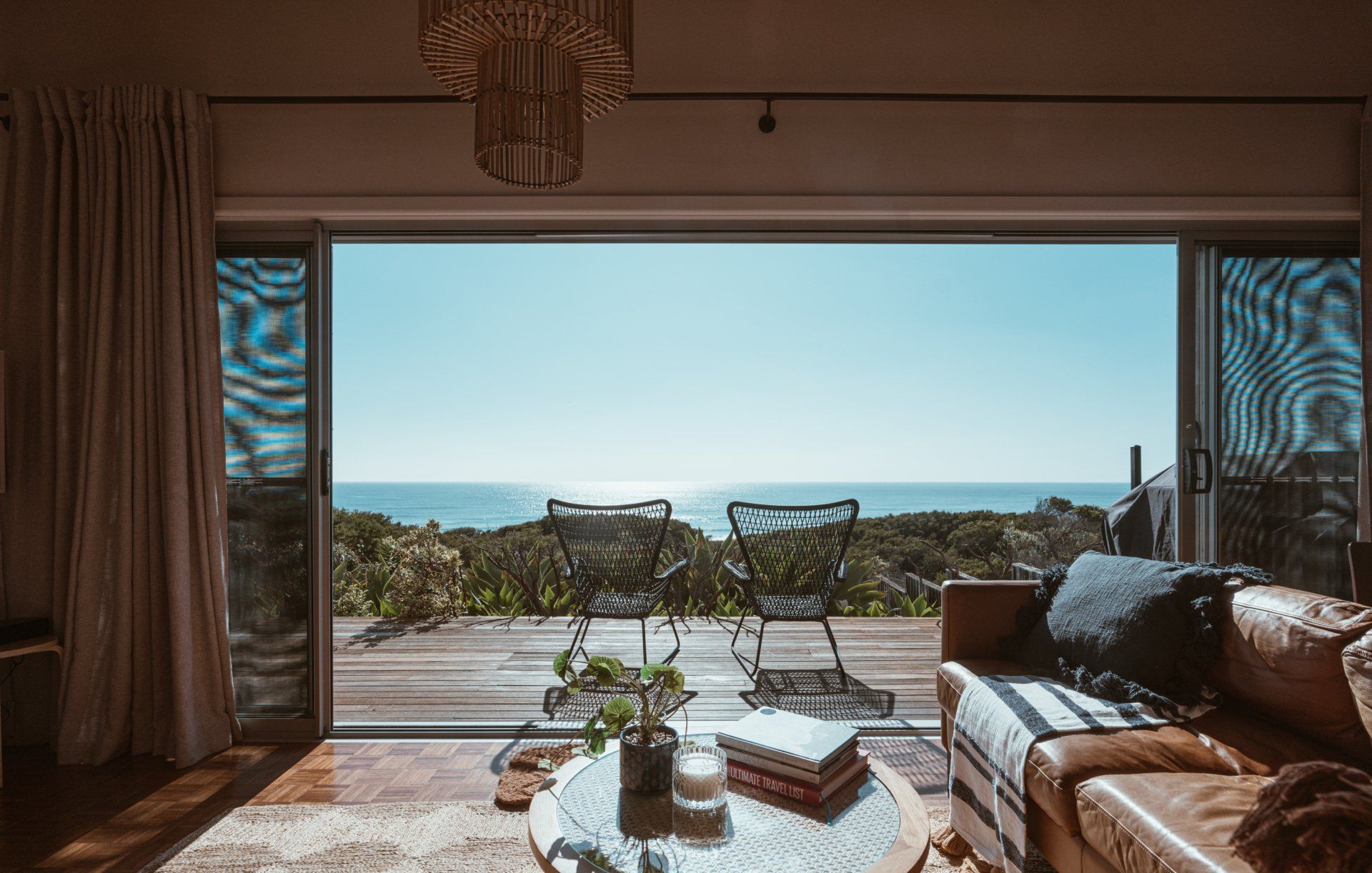 A living room with a couch , table and chairs and a view of the ocean.