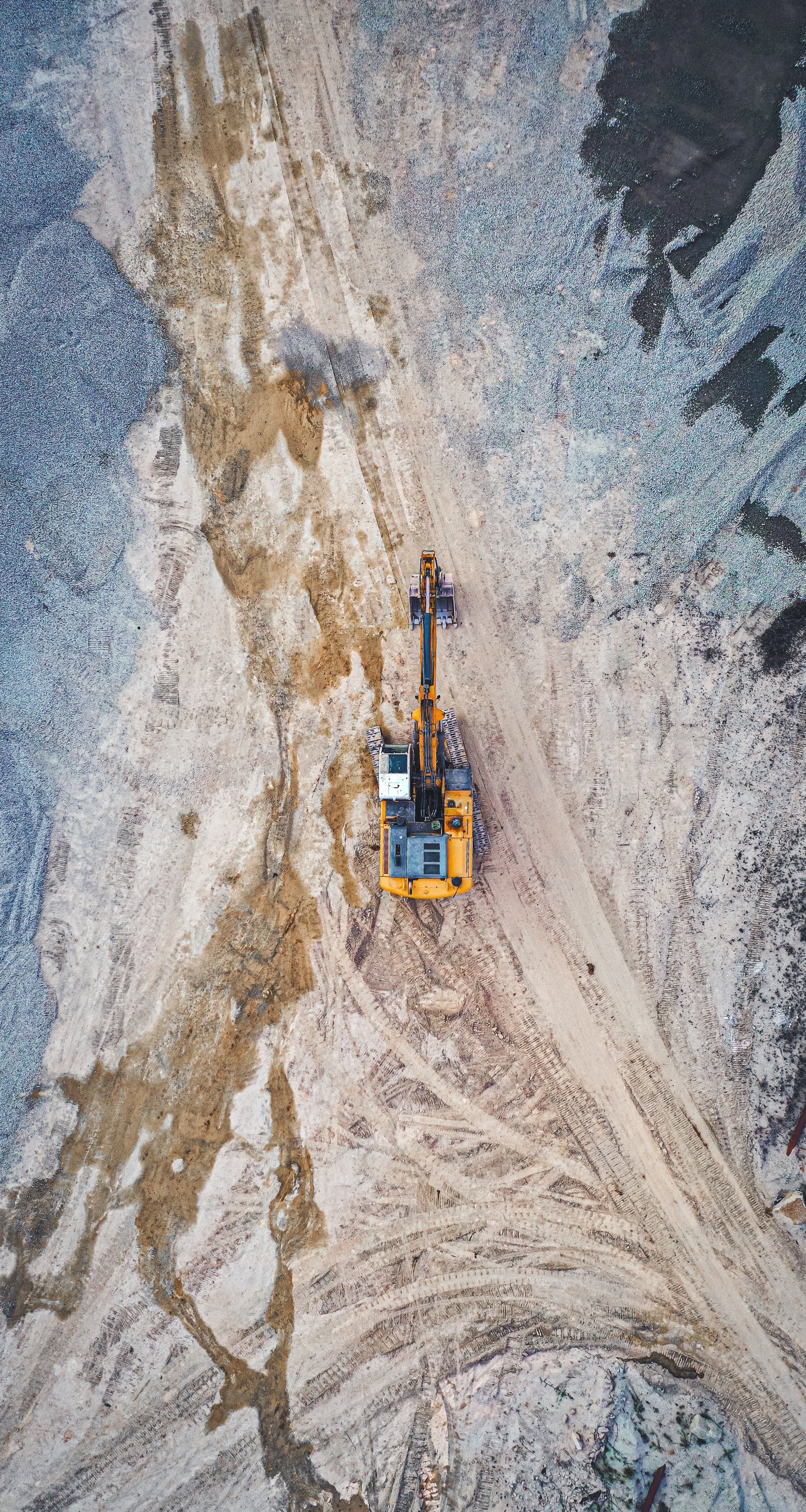 An aerial view of a yellow excavator in a quarry.