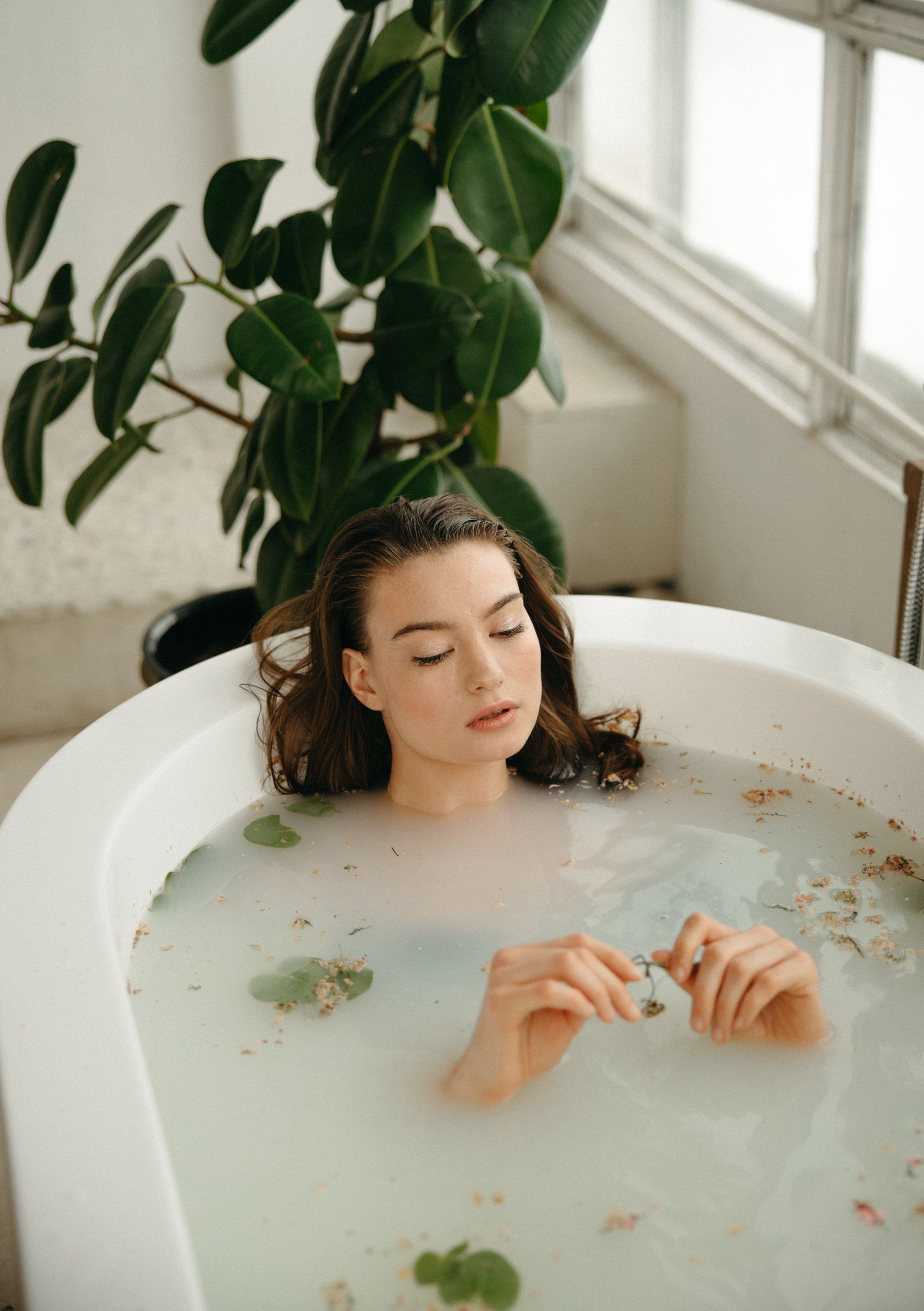 A woman is taking a milk bath in a bathtub.