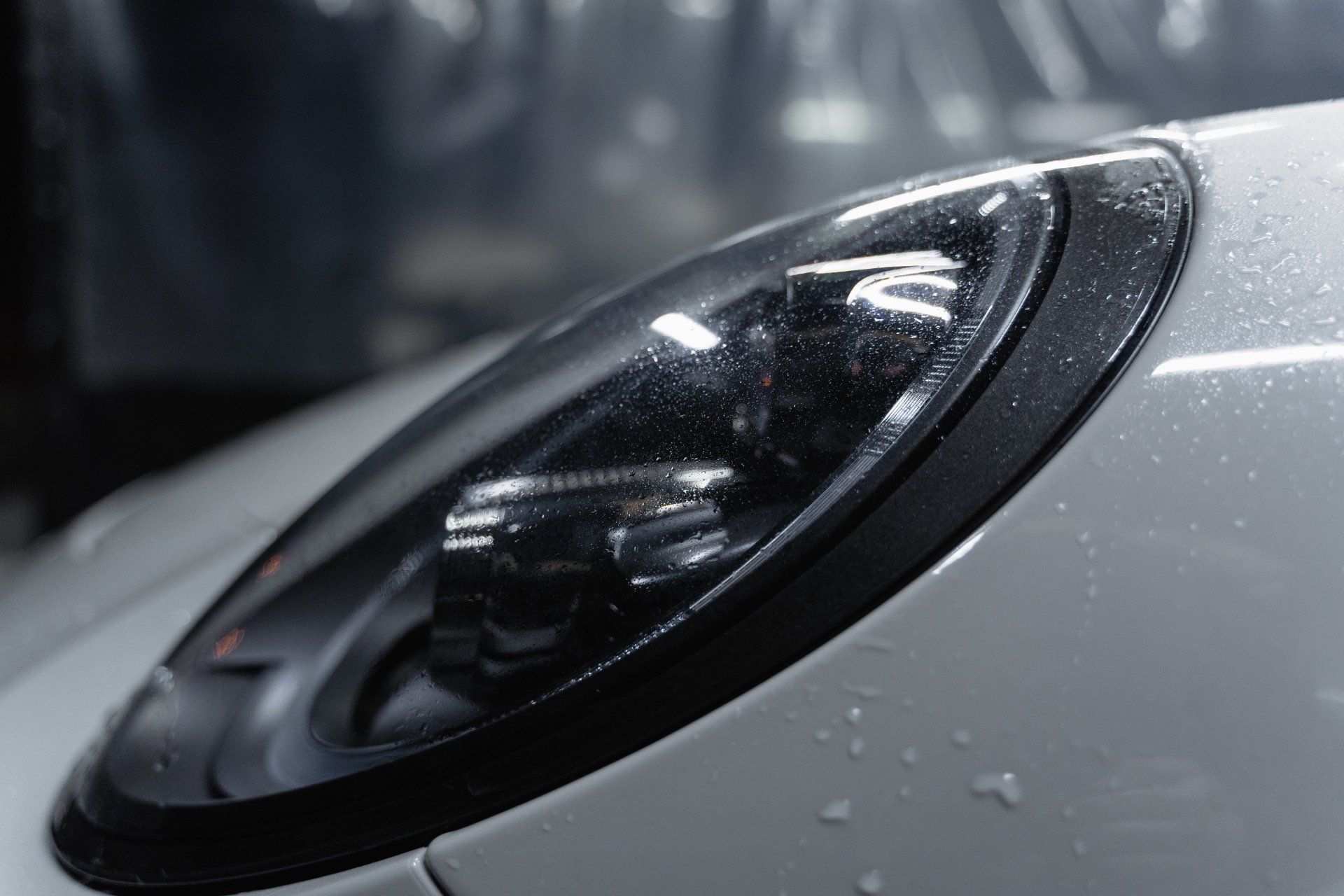Eine Nahaufnahme eines Autoscheinwerfers mit Wassertropfen darauf.