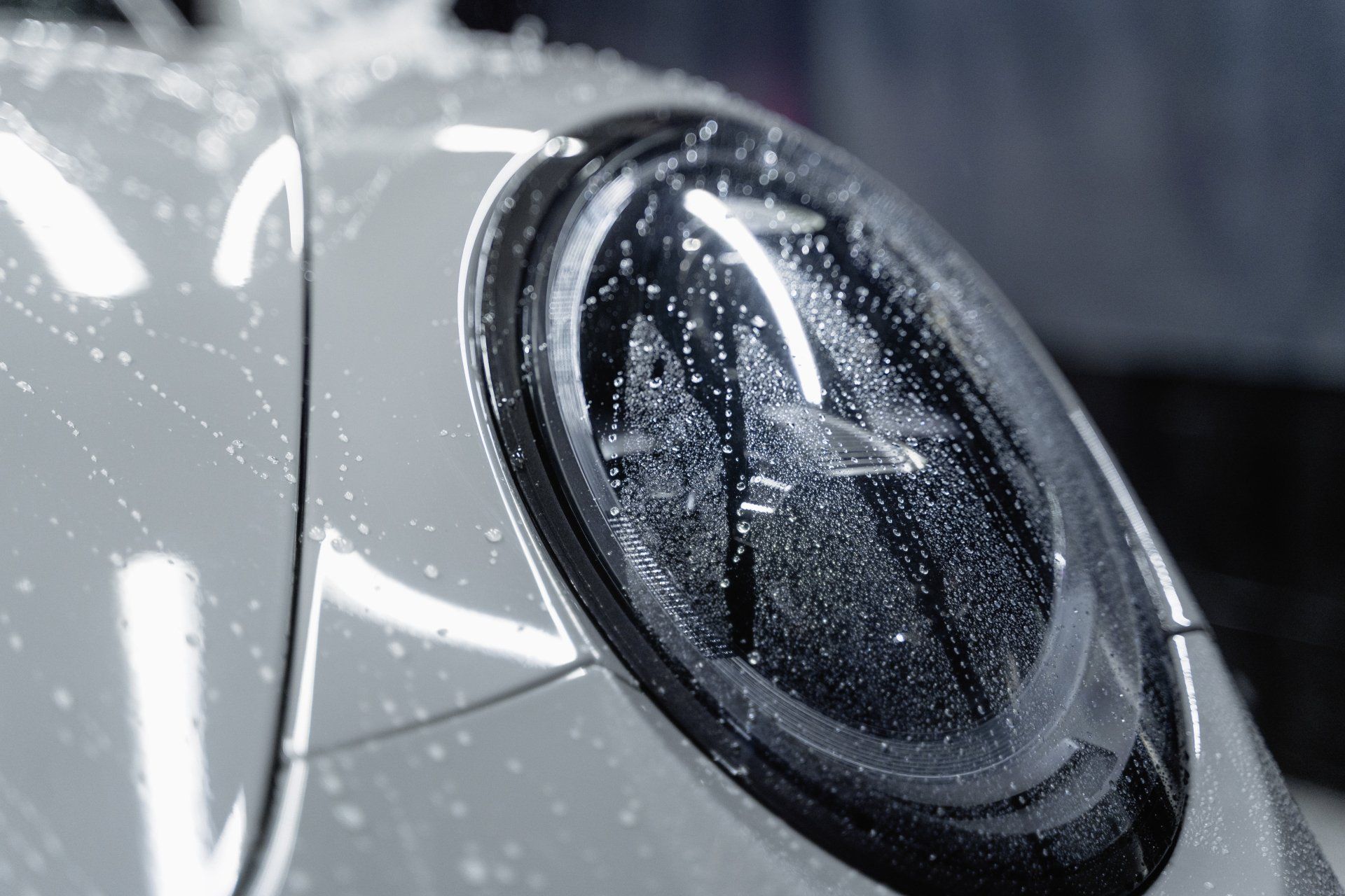 Eine Nahaufnahme eines Autoscheinwerfers mit Wassertropfen darauf.