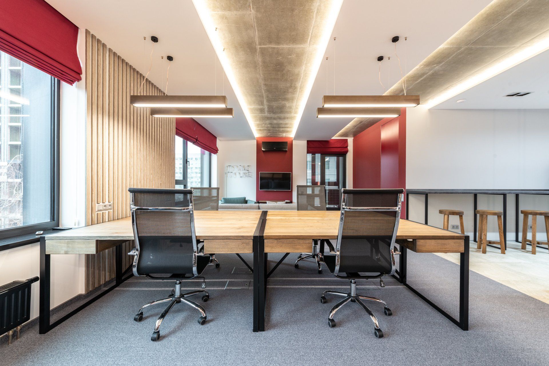 Open office space with desks, chairs, red accents, and decorative lighting.