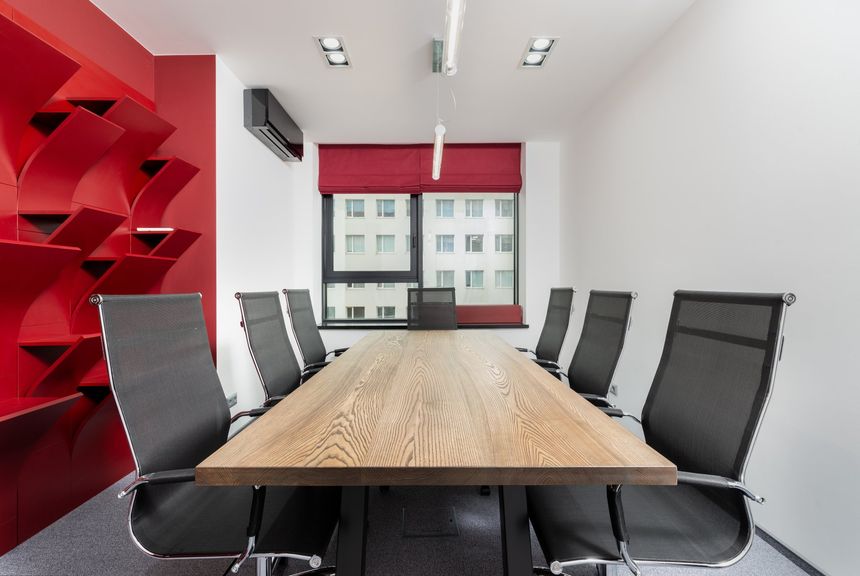 A conference room with a long wooden table and black chairs.