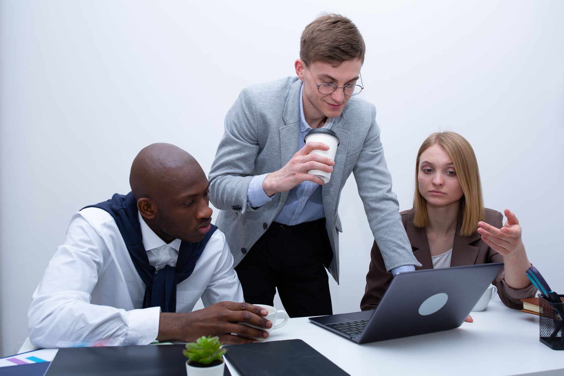 Um grupo de pessoas está sentado à mesa olhando para um laptop.