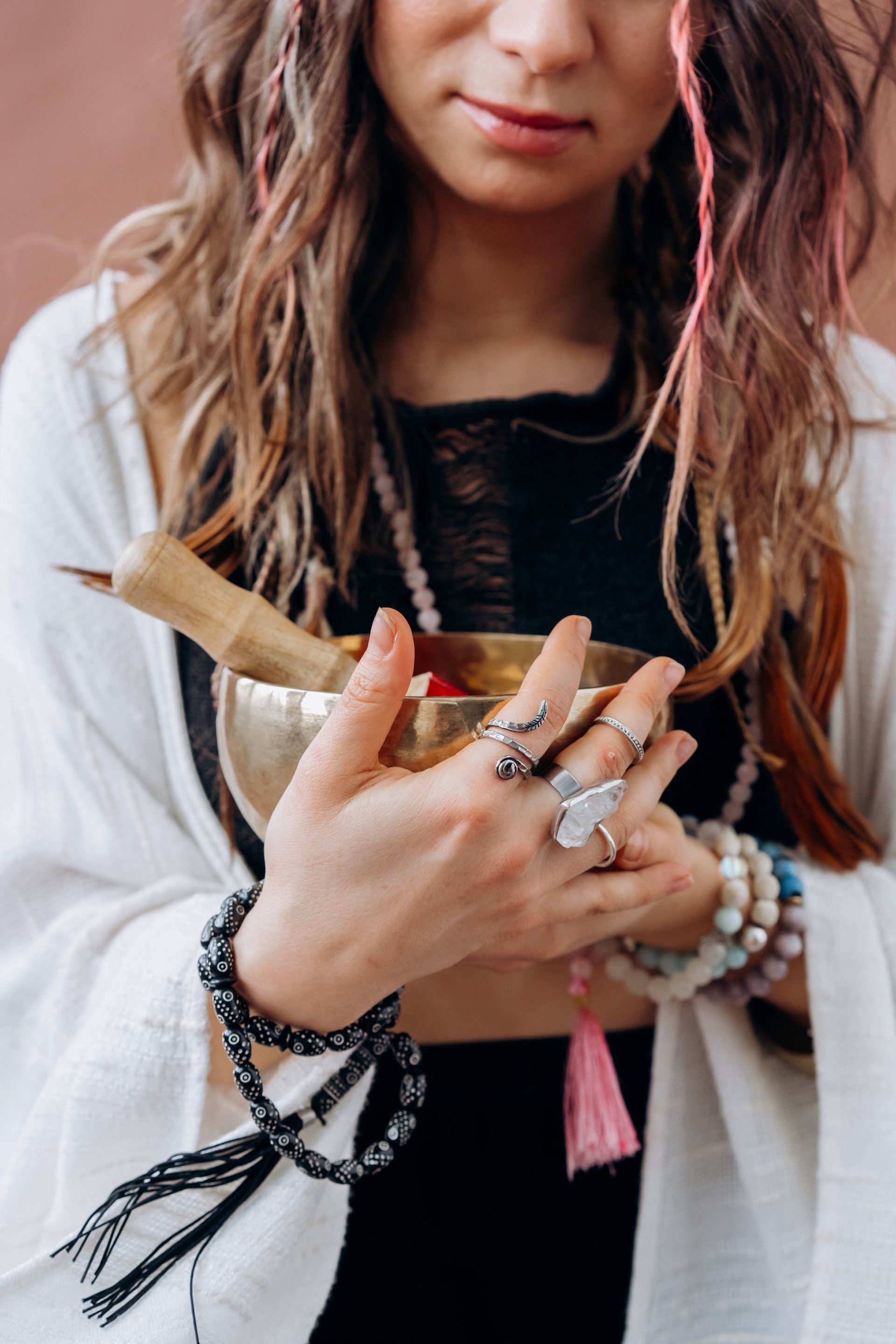 Woman holding a singing bowl, adorned with jewelry, offering spiritual practice.
