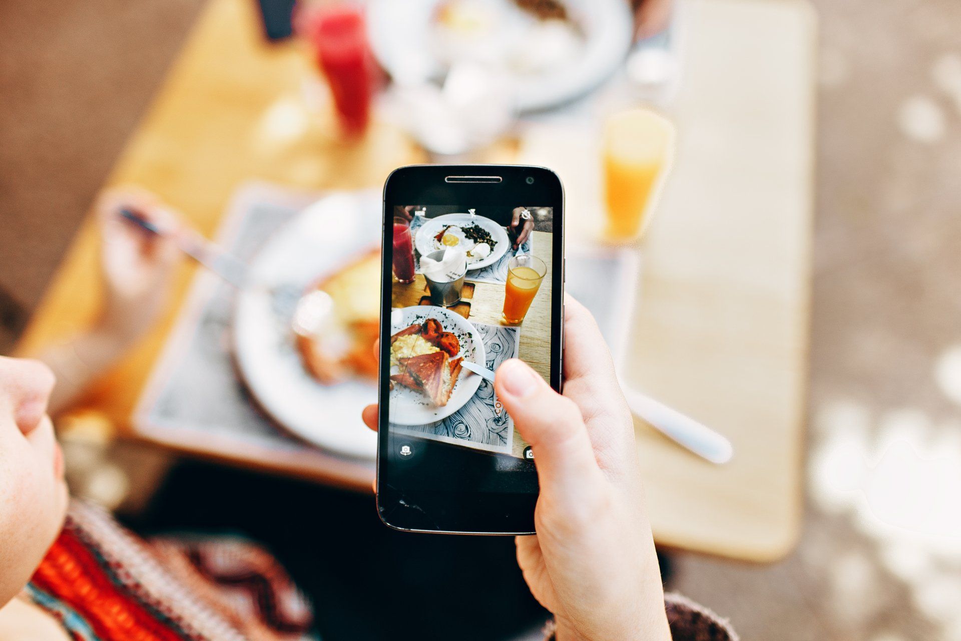 A person is taking a picture of a plate of food on a cell phone.