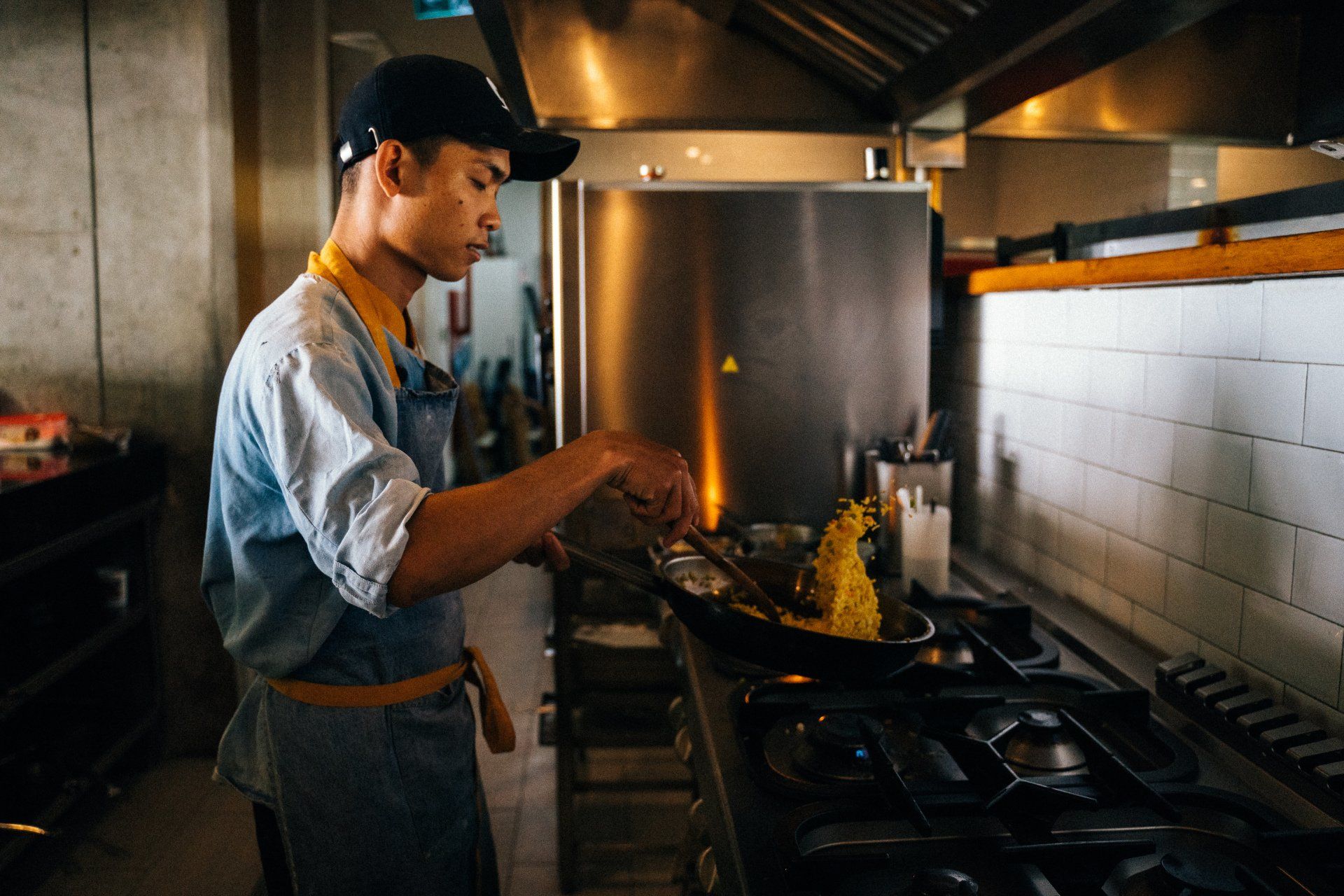 A man is cooking food on a stove in a kitchen.