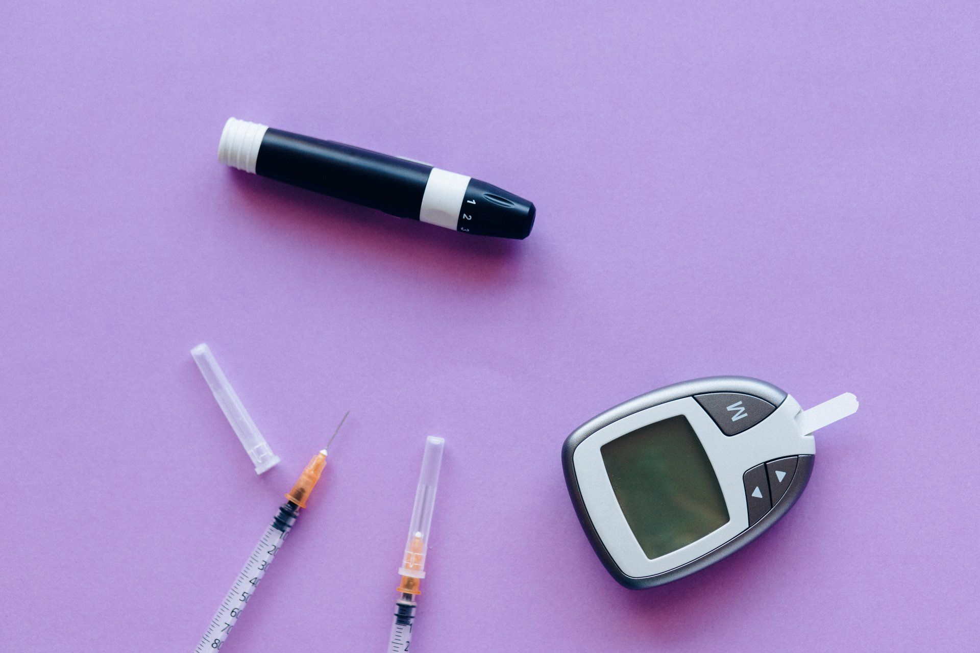 a few needles and diabetic instruments strug across a purple table