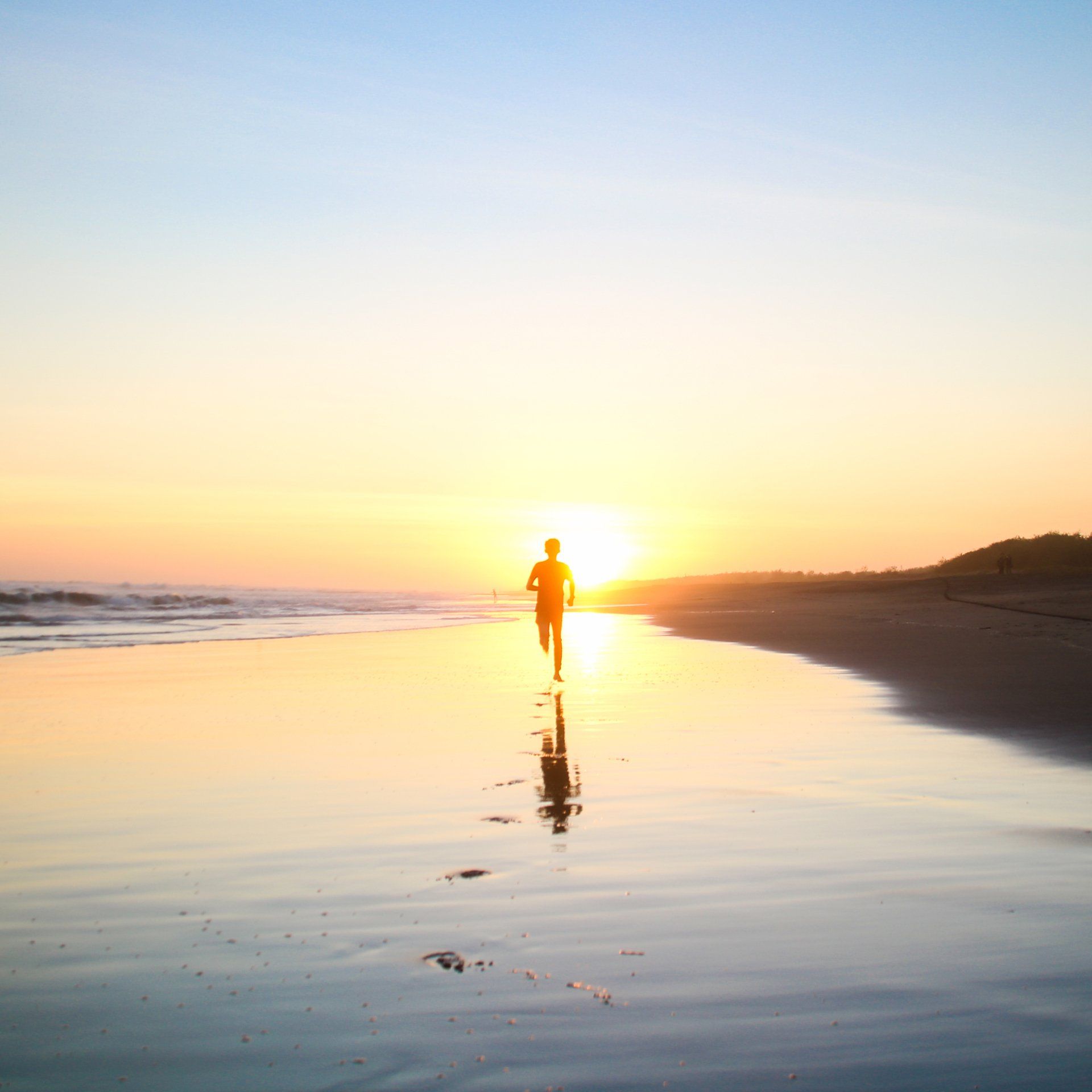 A person is running on the beach at sunset.