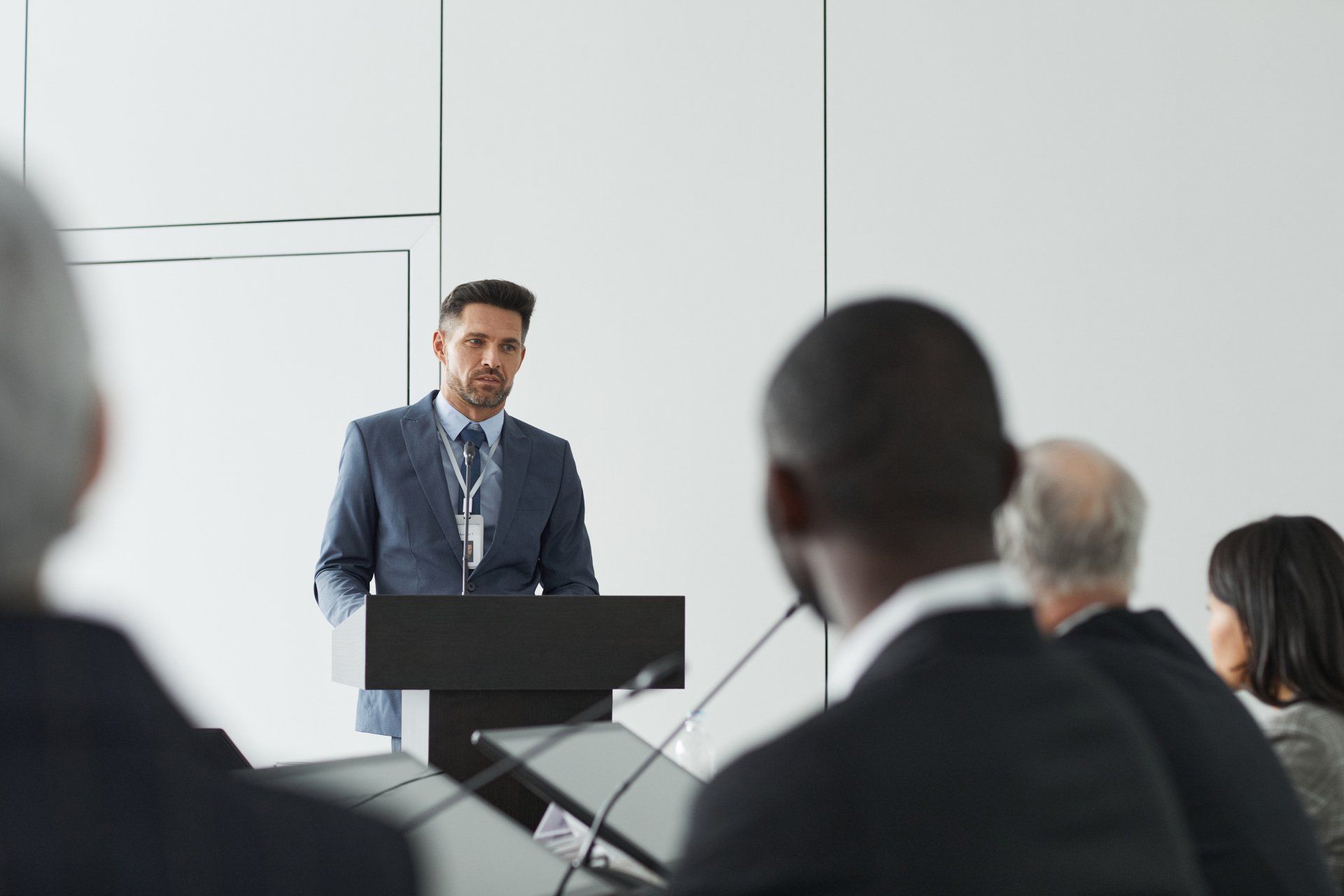 A man is giving a speech at a podium in front of a group of people and teaching for a better training.