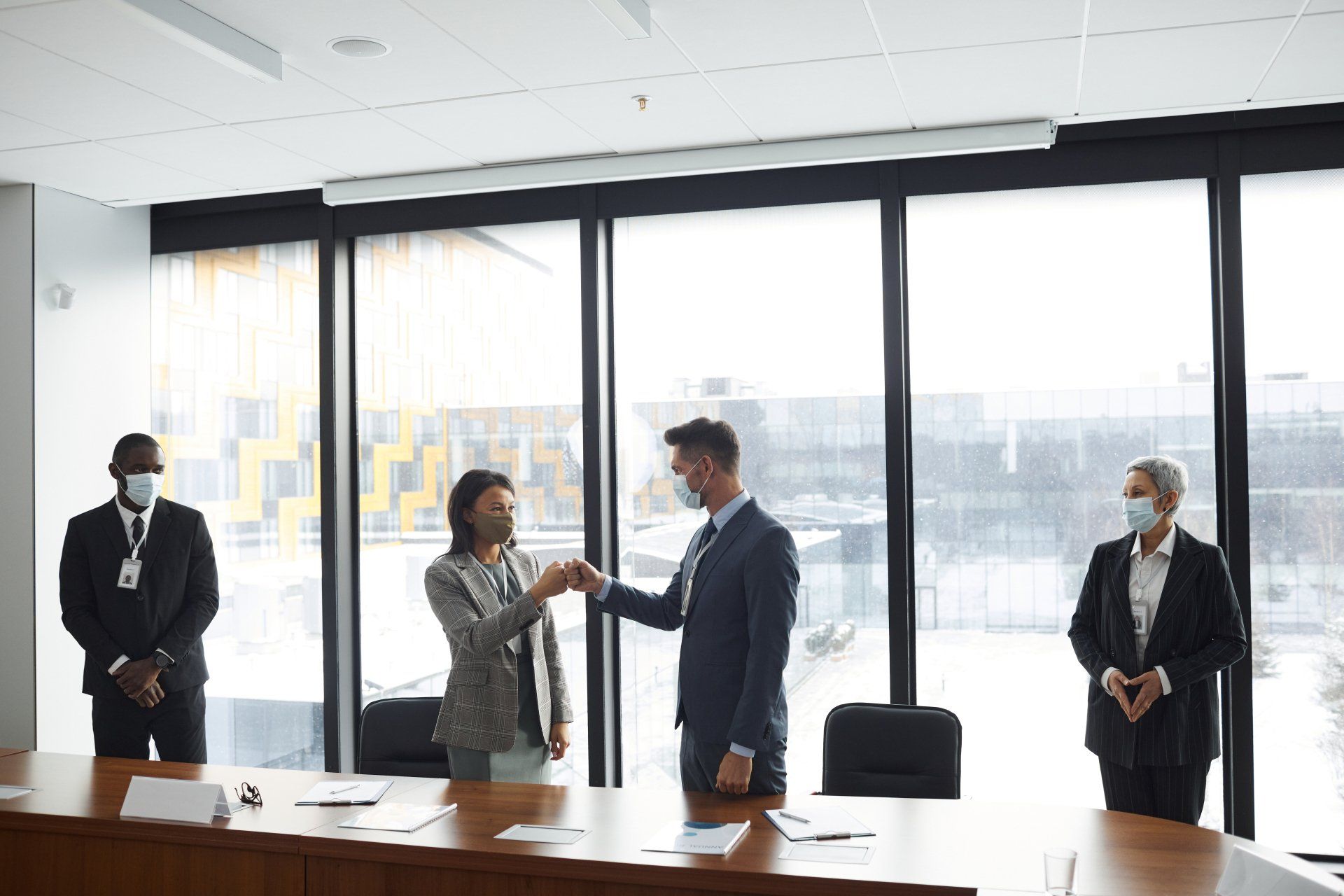 A group of people wearing masks and fist bumping during a business conference