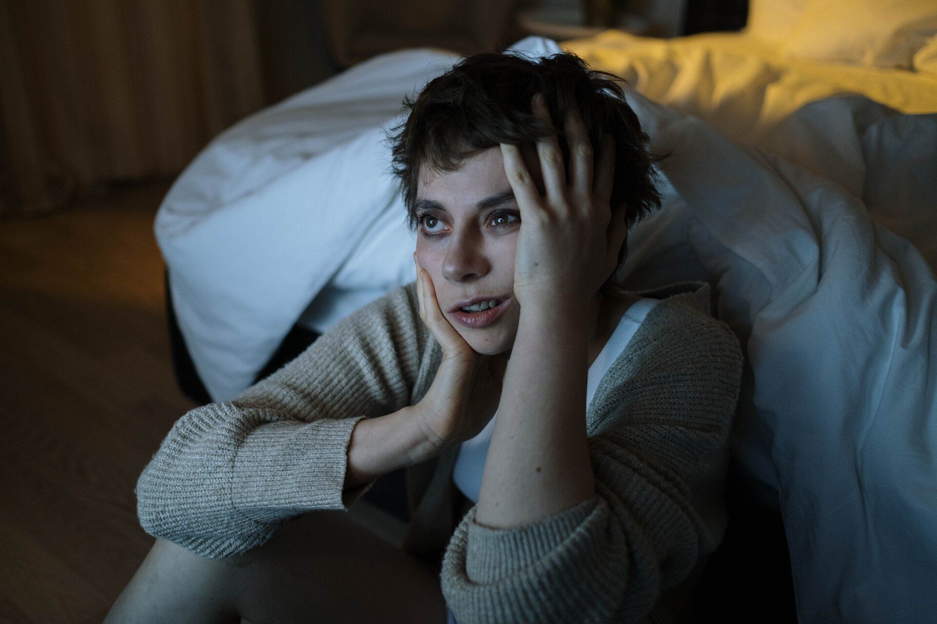 A woman is sitting on the floor with her hands on her head in front of a bed. how can ketamine help insomnia