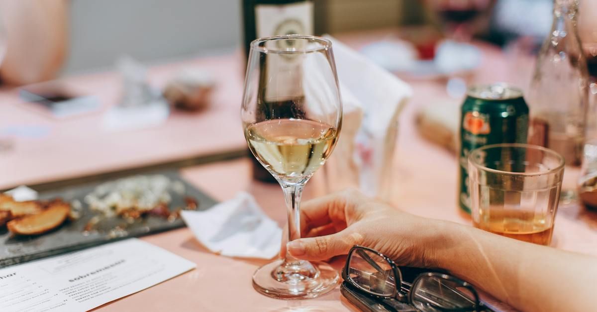A person is holding a glass of wine on a table.