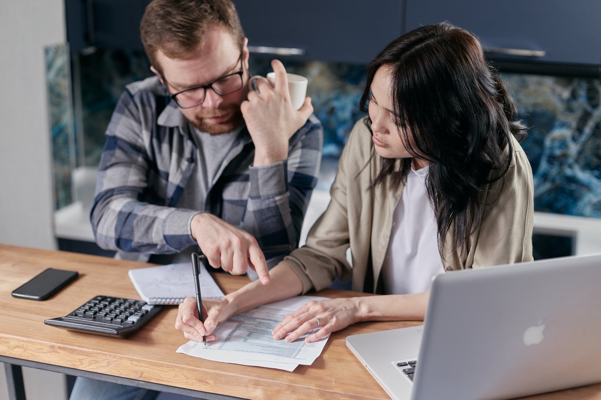 Two people looking over papers at a desk.