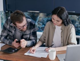 A man and a woman are sitting at a table looking at papers.