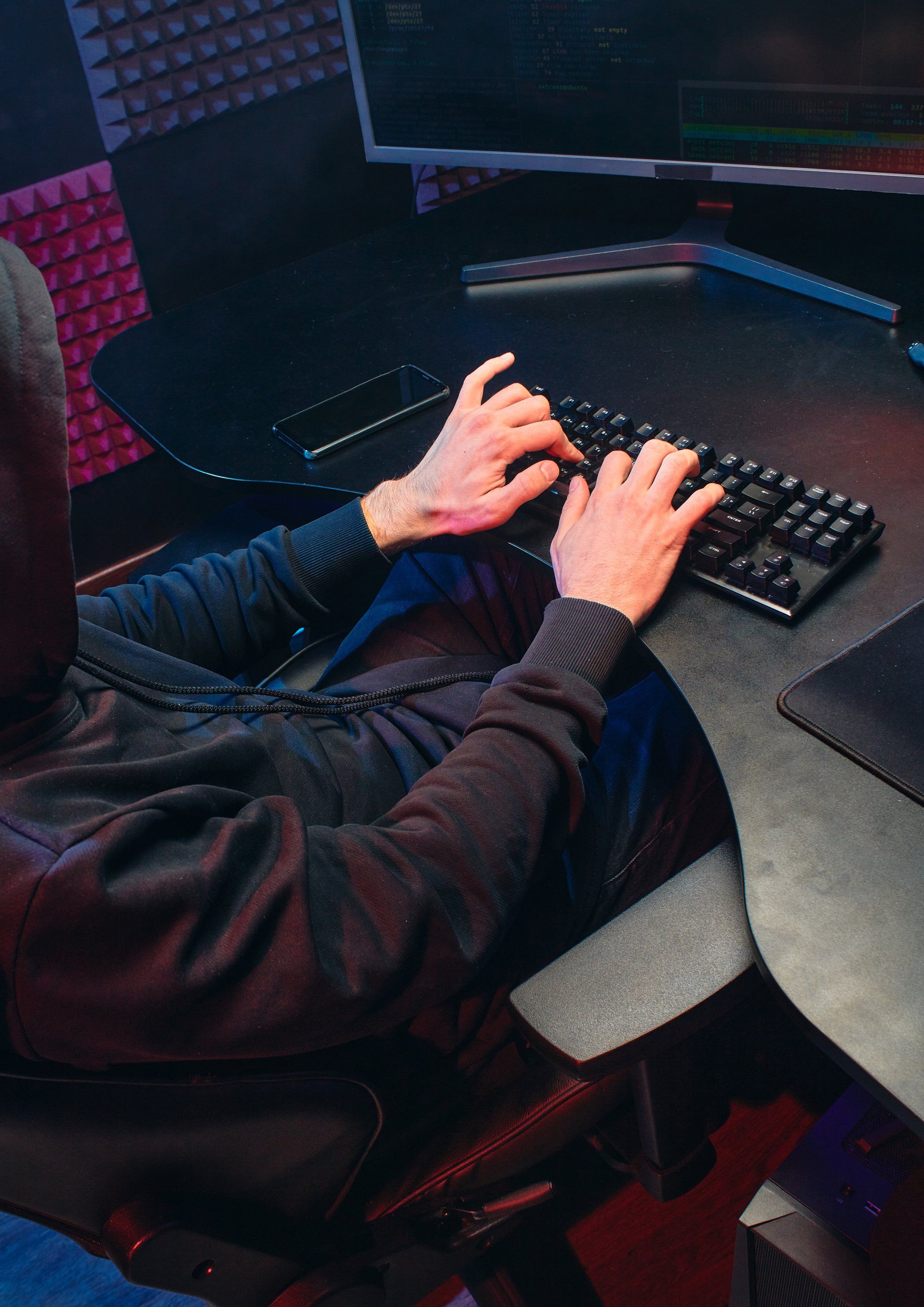 Hacker typing a malicious email to an unsuspecting employee.