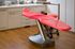 Red dental chair in a dentist's office with wood flooring and white cabinets.