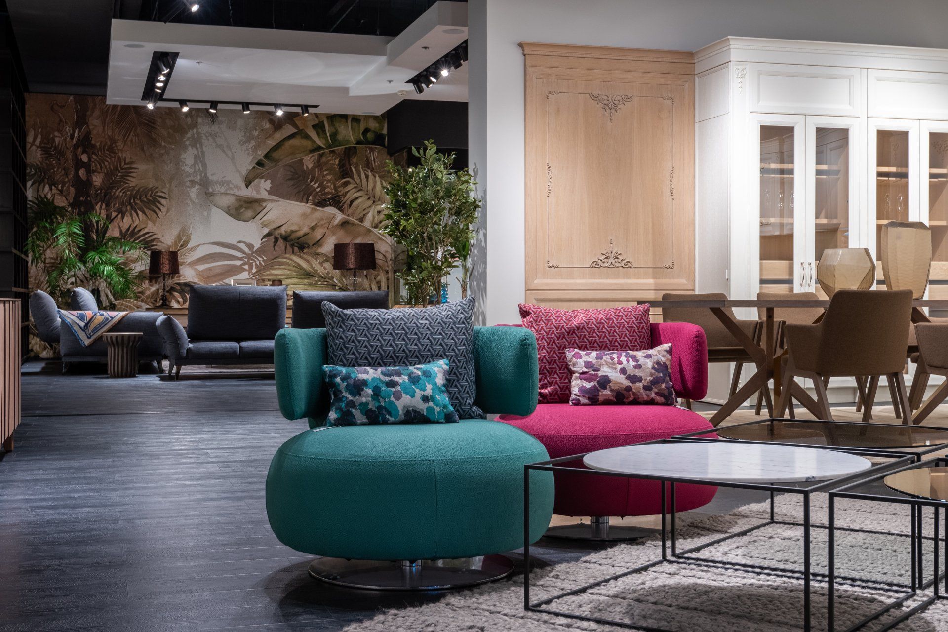 Modern furniture showroom featuring colorful chairs, glass tables, and a dining set.