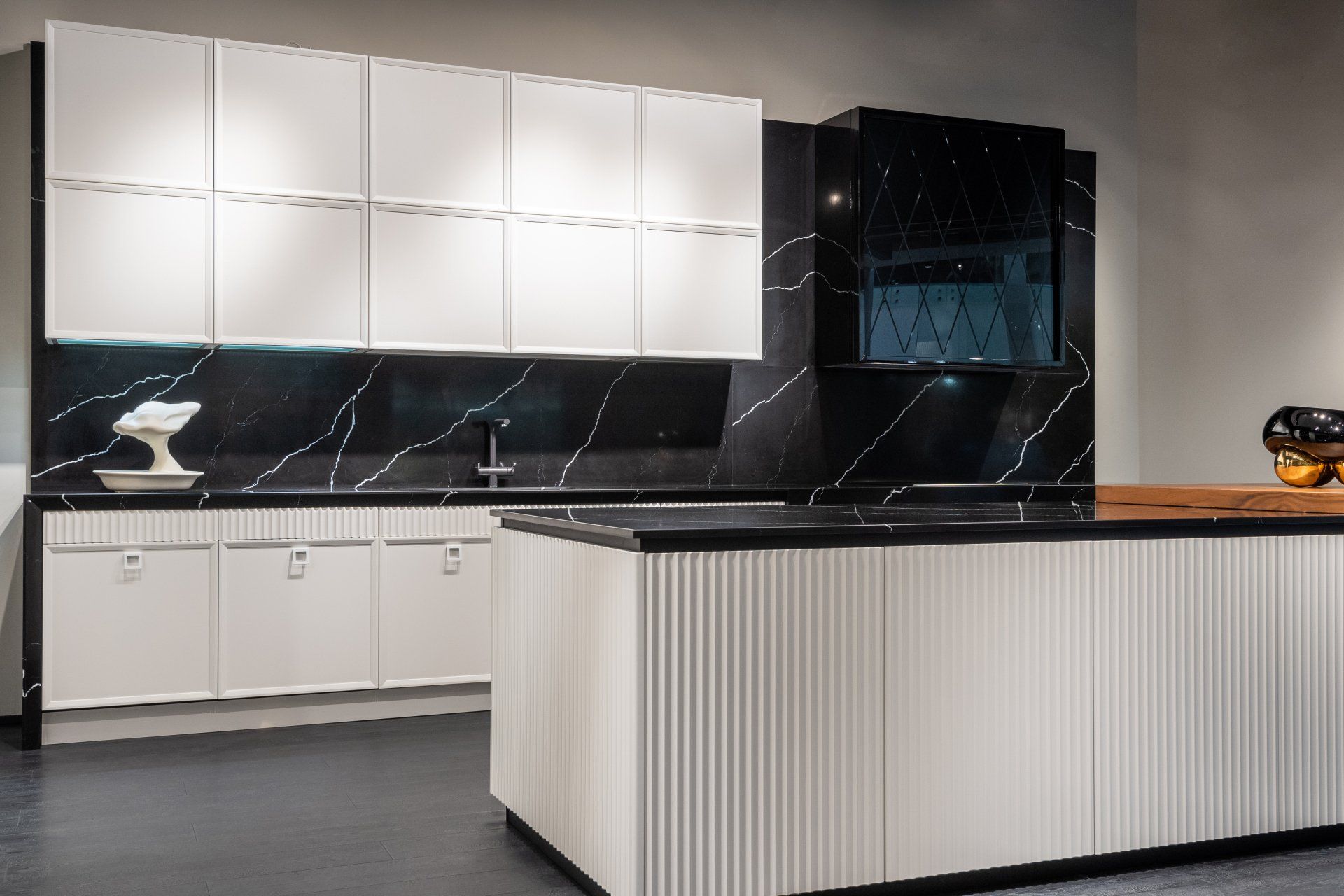 Modern kitchen with white cabinets, black marble backsplash, and a striped island