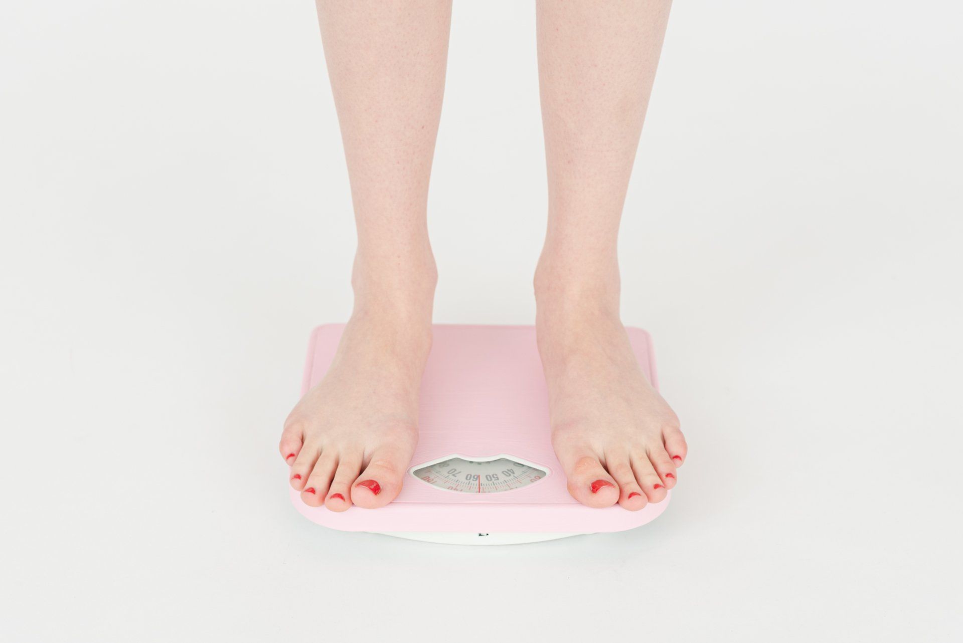 A woman is standing on a pink scale.