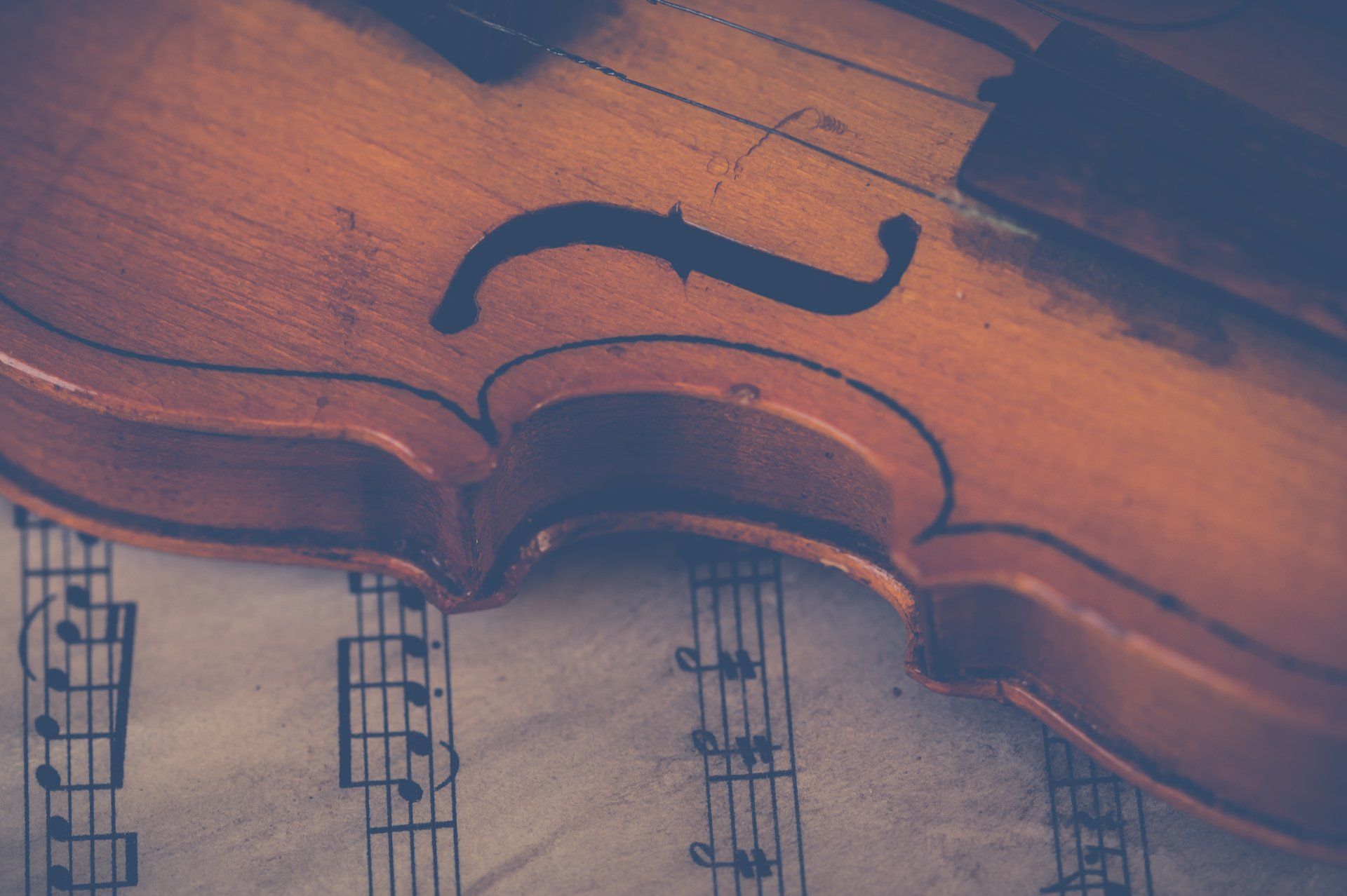 Violin on sheet music, close-up shot. The violin is brown, the music is in black notes on white paper.
