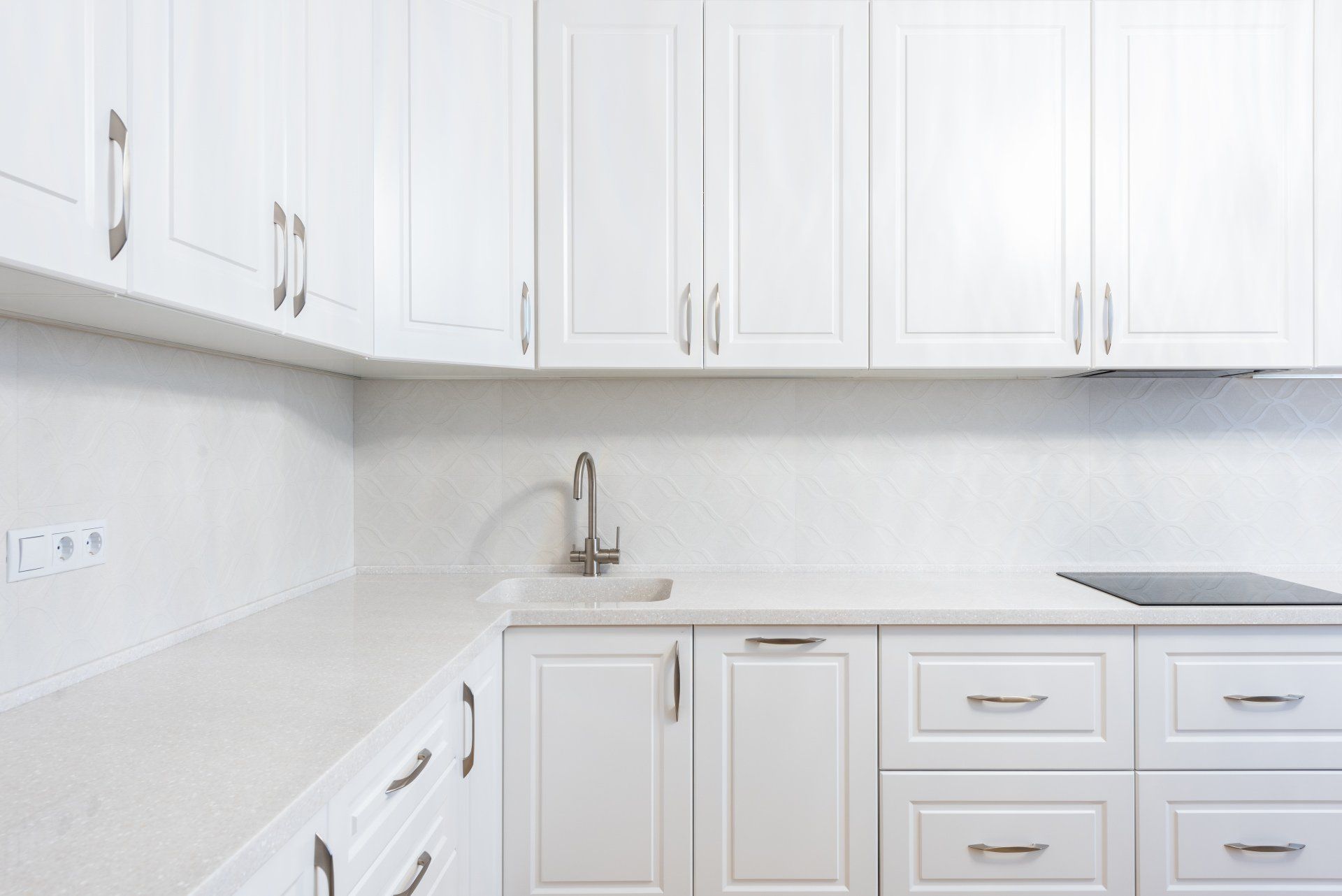 a kitchen with white cabinets , drawers , a sink and a stove .