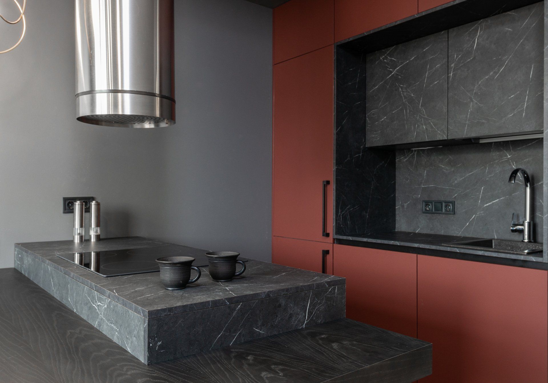 A kitchen with red cabinets and a stainless steel hood.