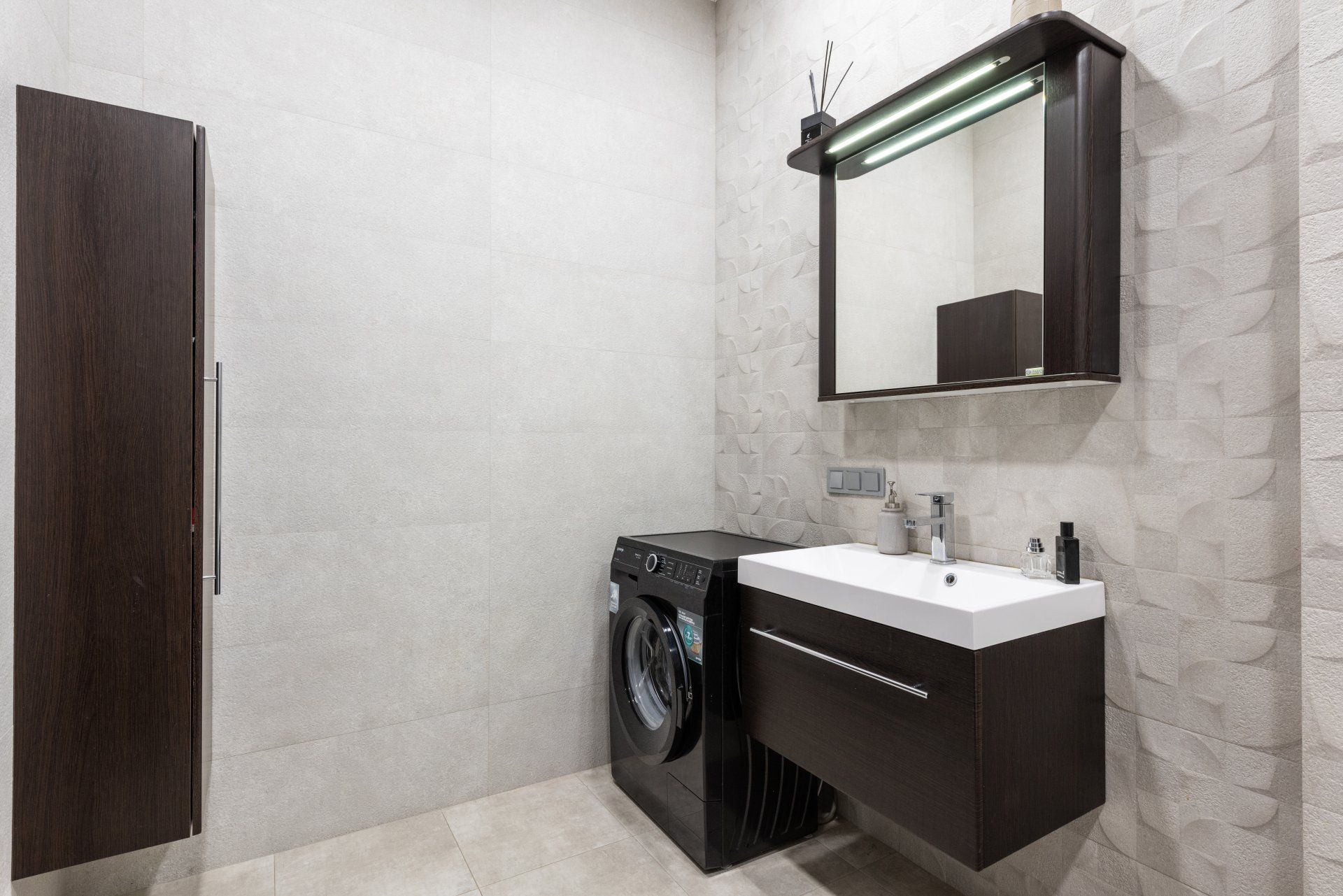 A bathroom with a sink , washer and dryer.