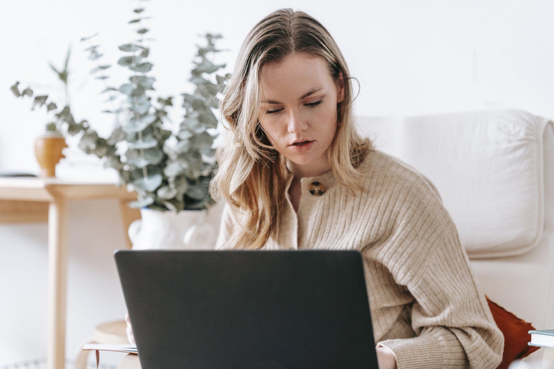 A woman is sitting on a couch using a laptop computer.