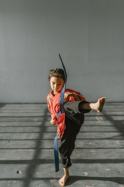 A young boy is practicing martial arts in a gym.