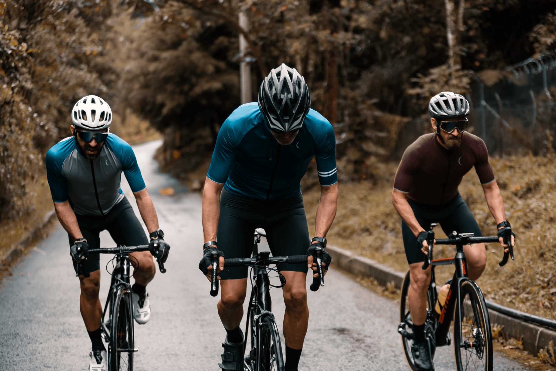 Three men are riding bicycles down a road.