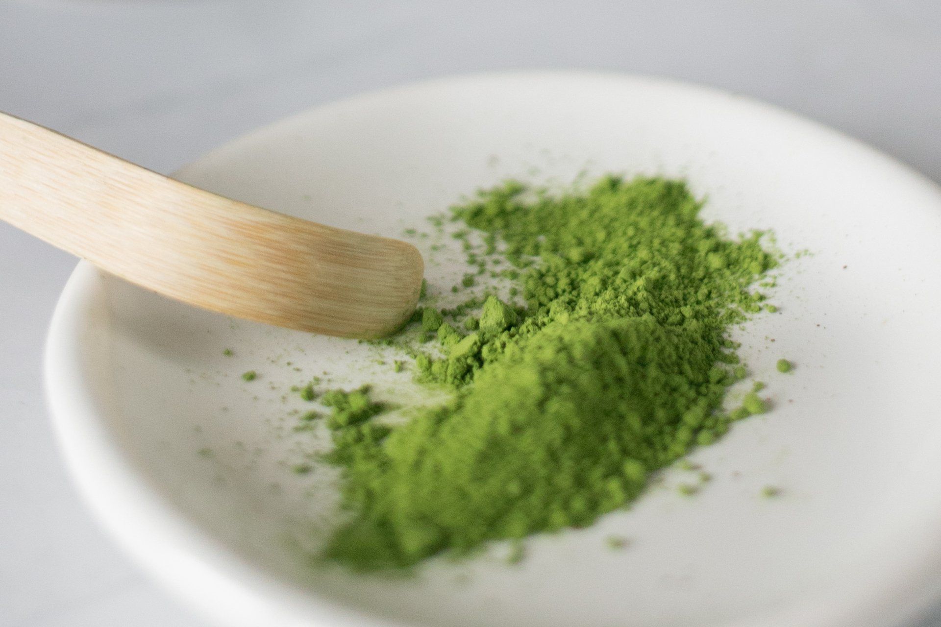 A white plate topped with green powder and a wooden spoon.