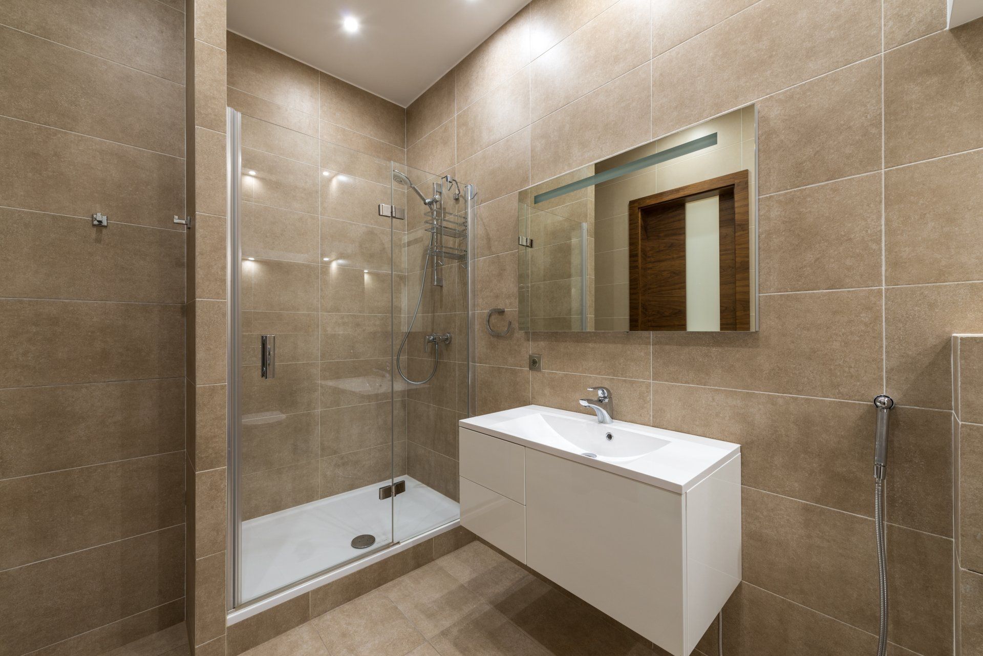 A bathroom with a sink , shower and mirror.