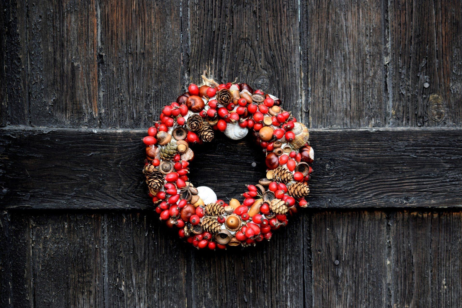 A christmas wreath is hanging on a wooden door.