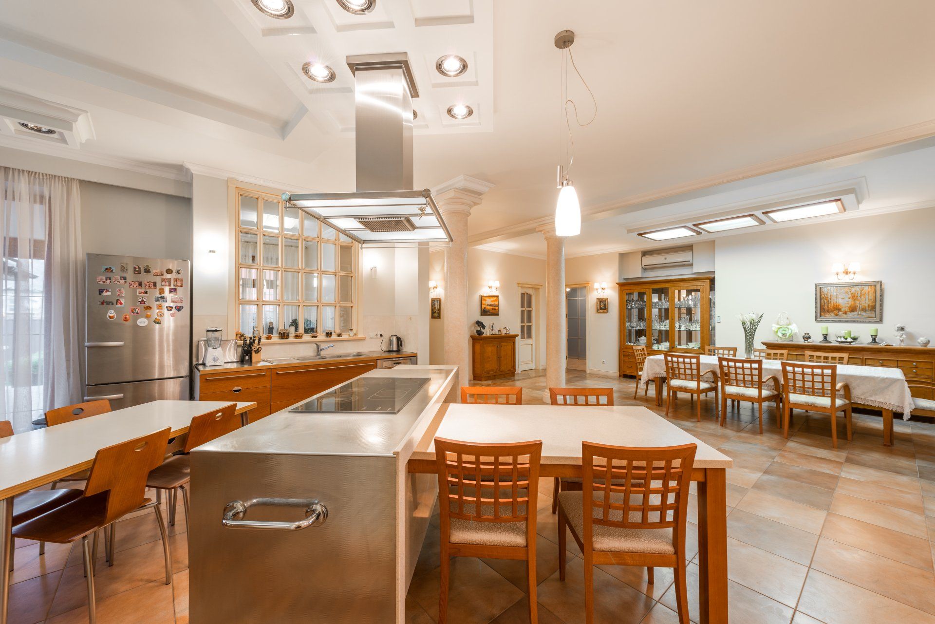 A large dining room with tables and chairs and a kitchen.