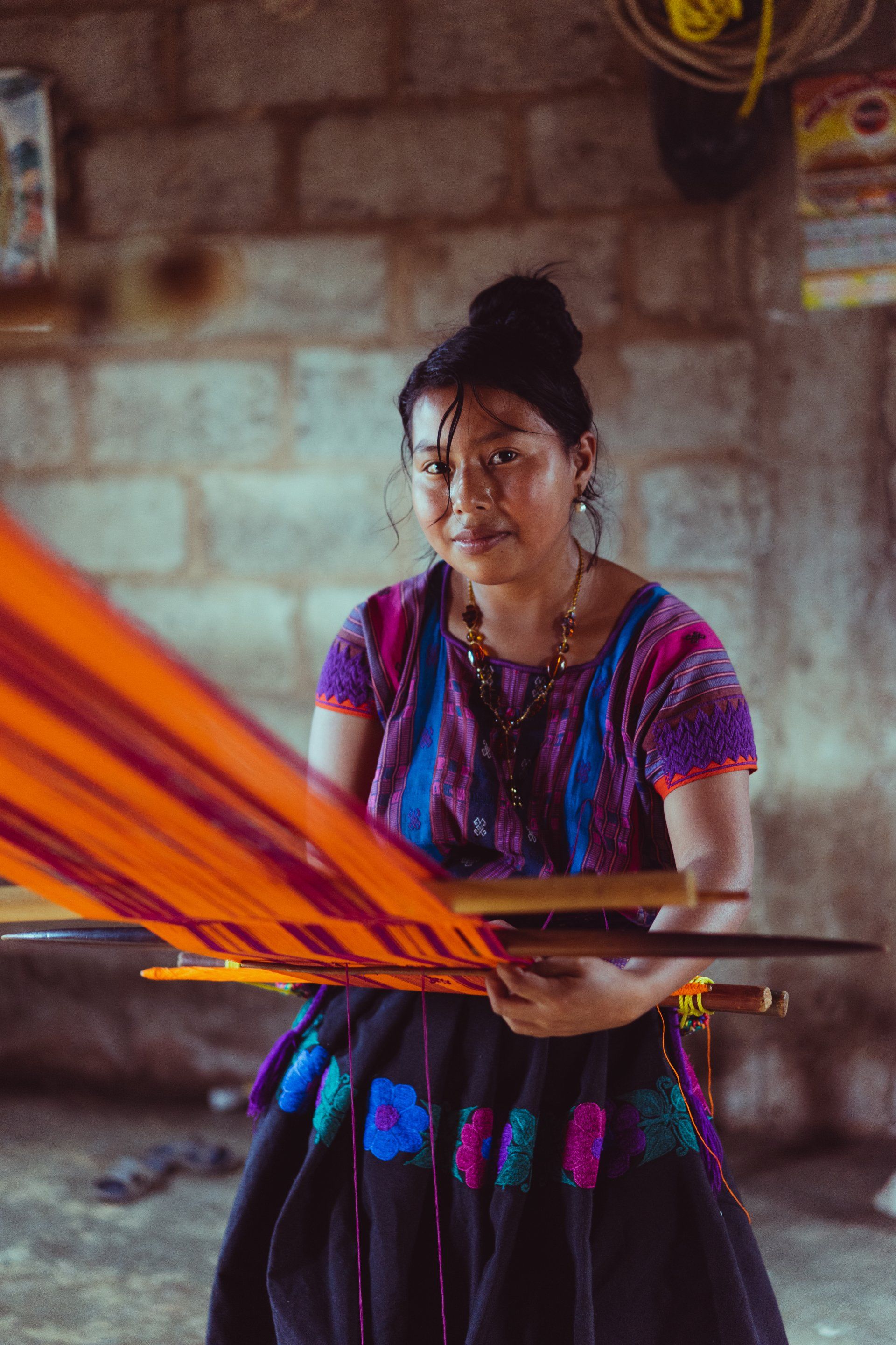A woman in a colorful dress is holding a piece of fabric.