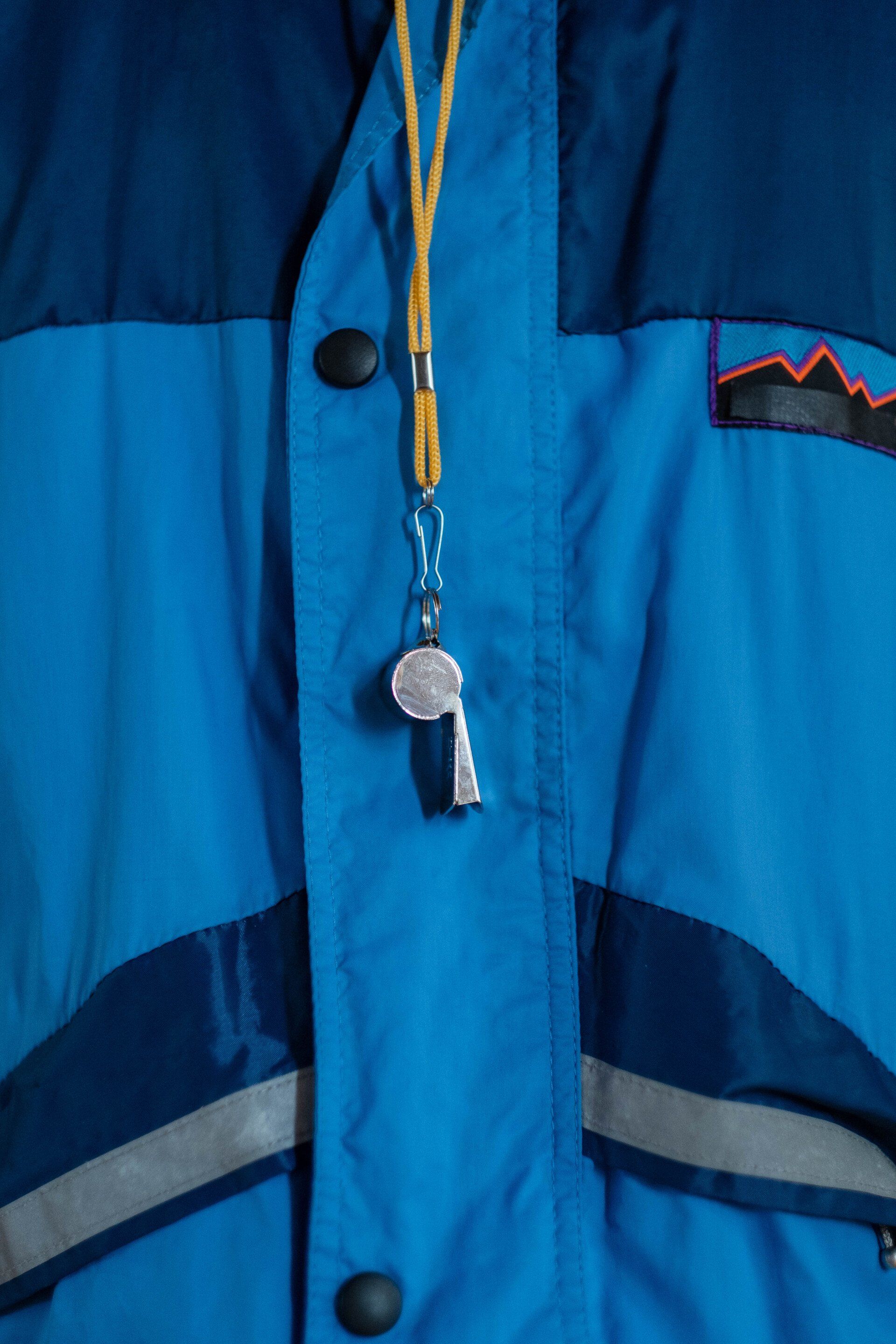 A blue jacket with a whistle attached to it