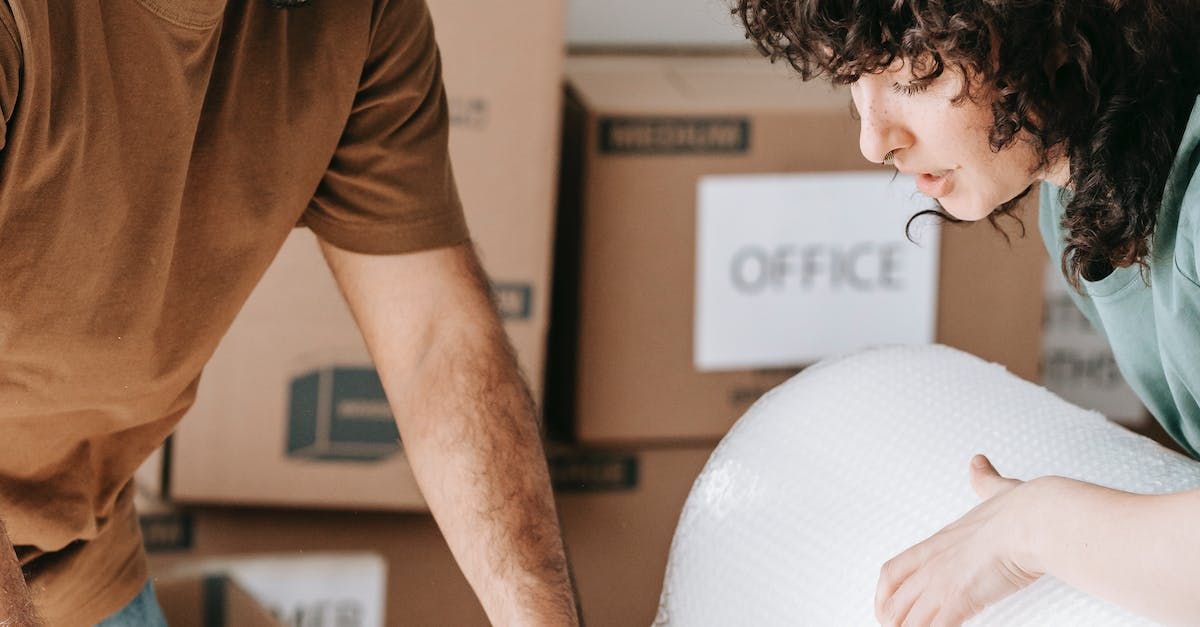 A man and a woman are standing next to each other in front of moving boxes.