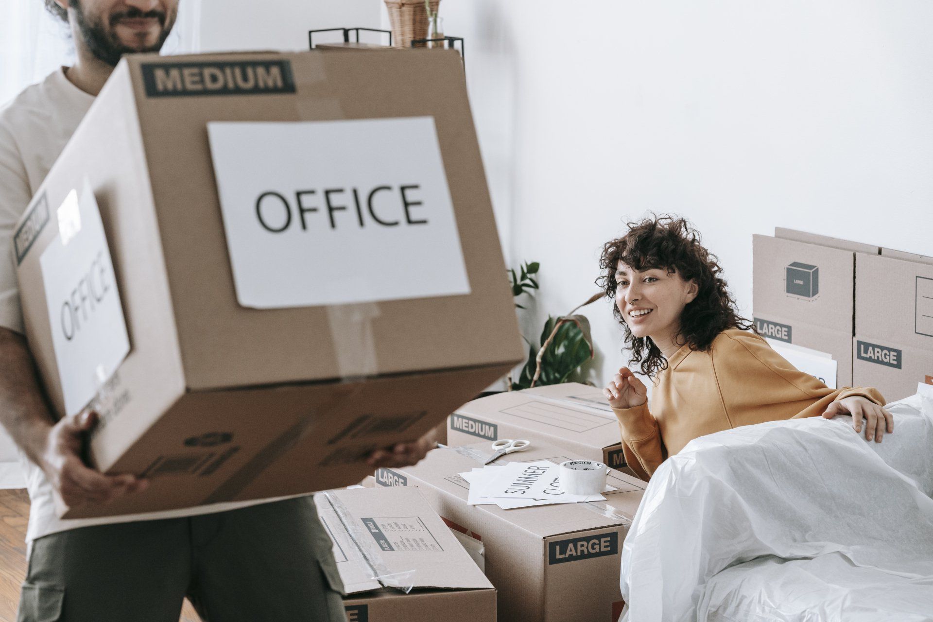 People moving cardboard boxes labeled office in a bright room